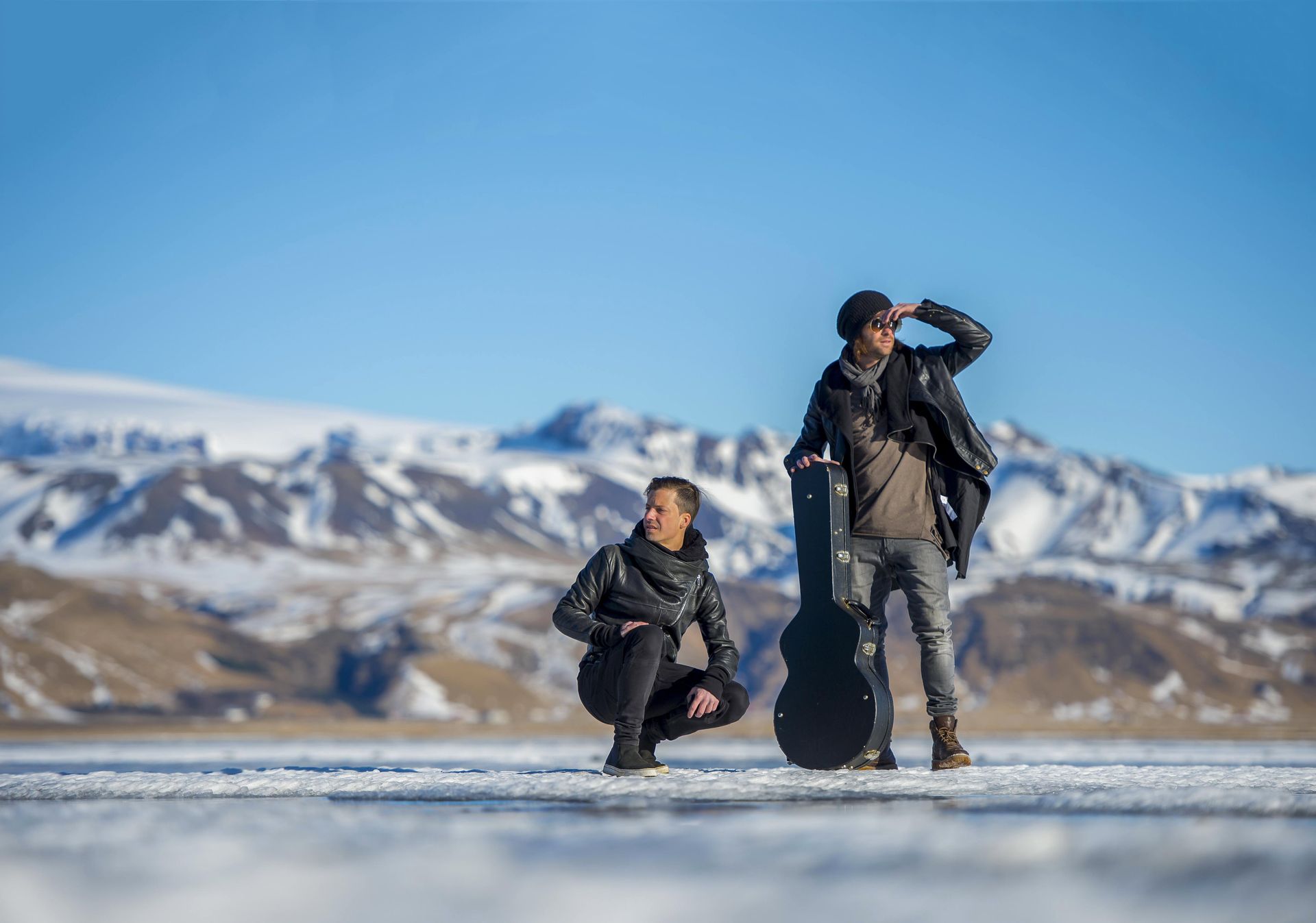 Due uomini sono in piedi uno accanto all'altro nella neve con in mano delle chitarre.