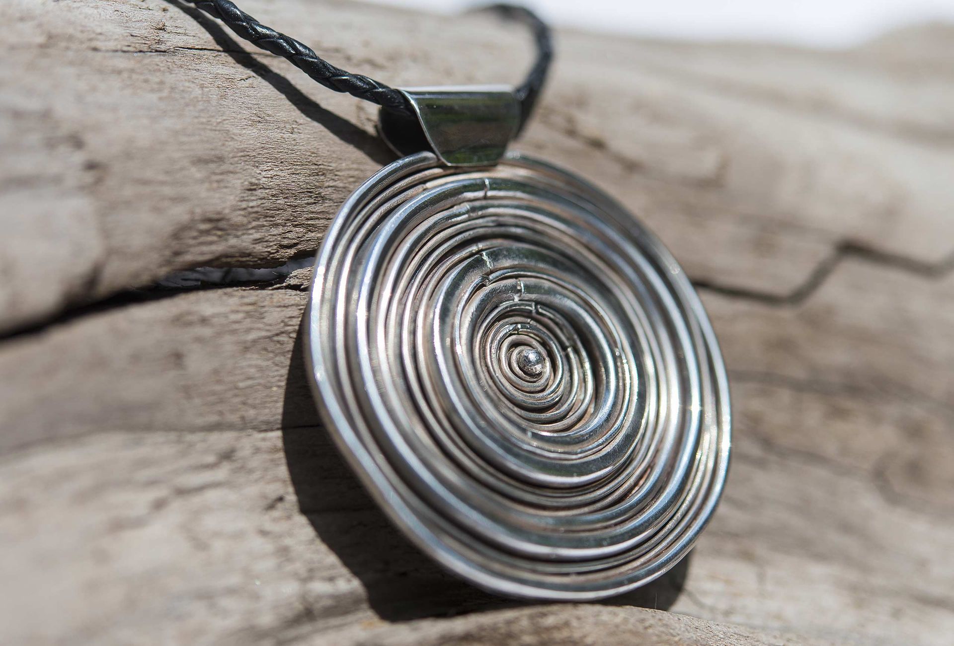 Un ciondolo d'argento è posato su un pezzo di legno.