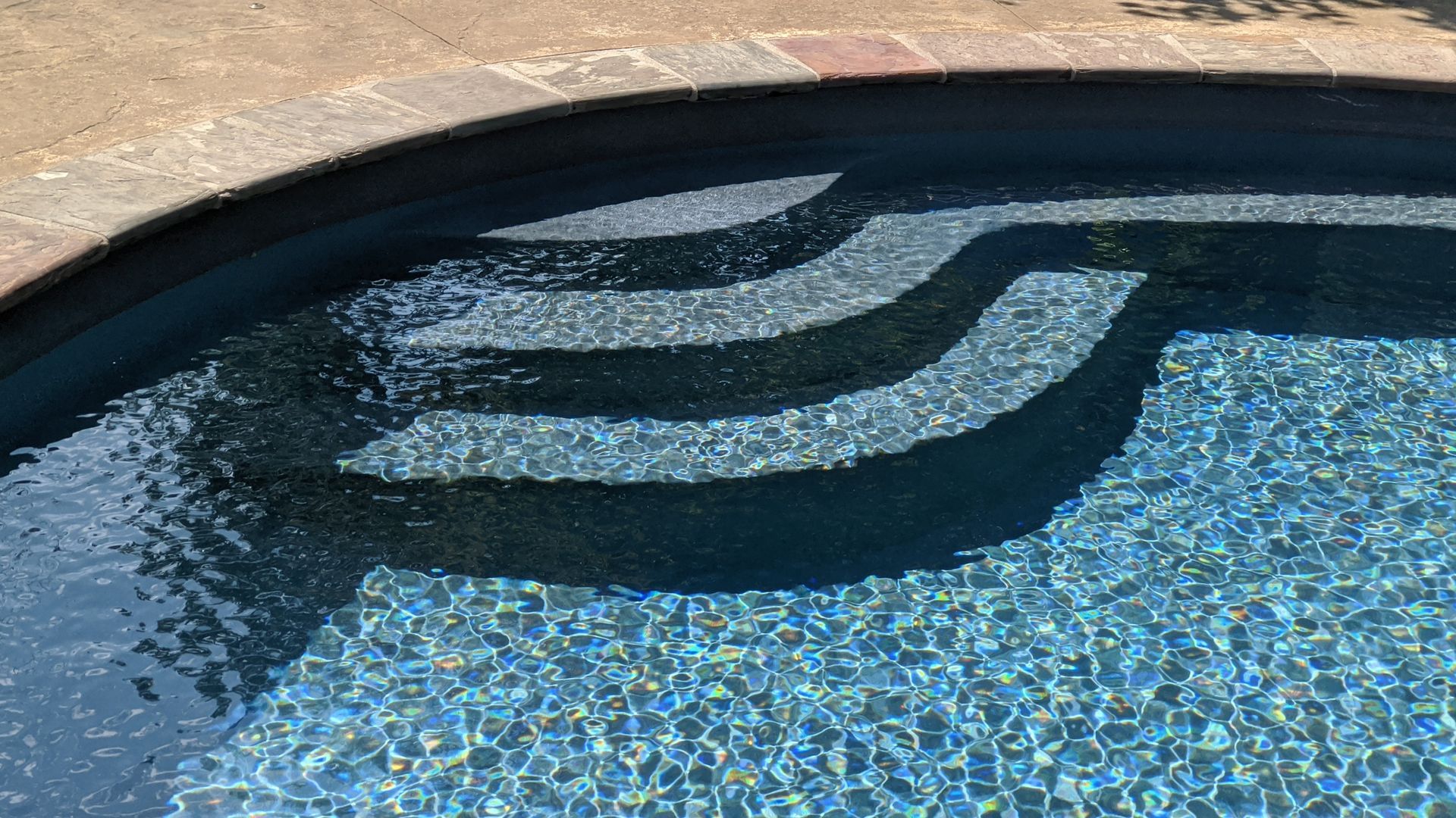 Green inflatable tube floating in a clear blue swimming pool.