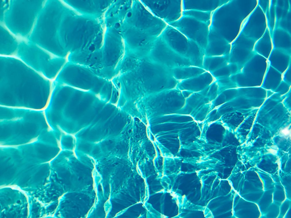 Clear, turquoise water surface with sunlight creating shimmering patterns.