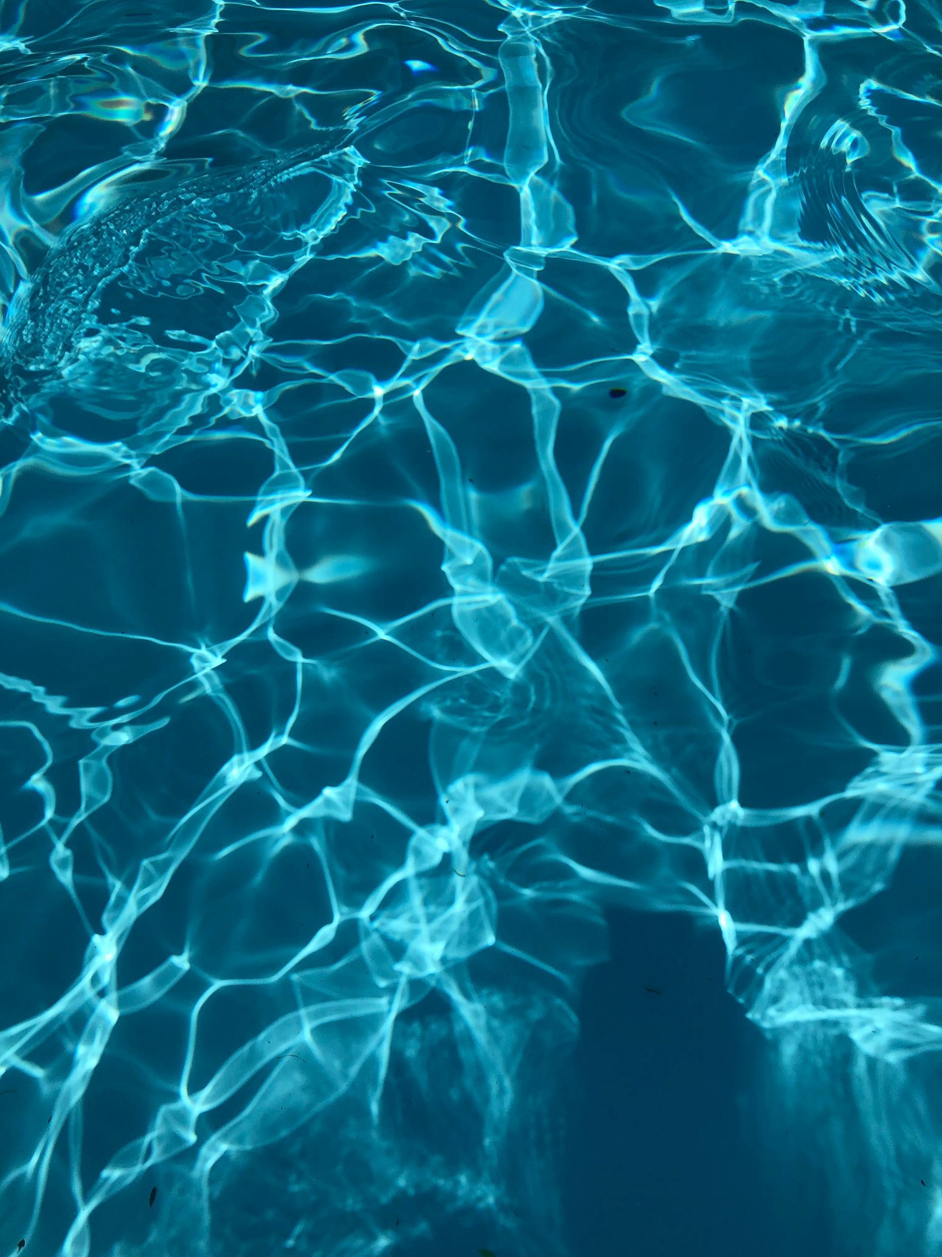 Clear, turquoise water with sun reflections creating bright, shimmering patterns.