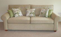 reupholstered sofa in taupe with floral fabric cushions