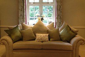 gold fabric upholstered settee with stack of cushions