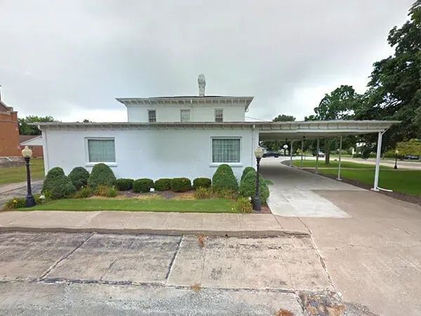 Hunter Funeral Home, white building with black lettering, covered driveway, cloudy day.
