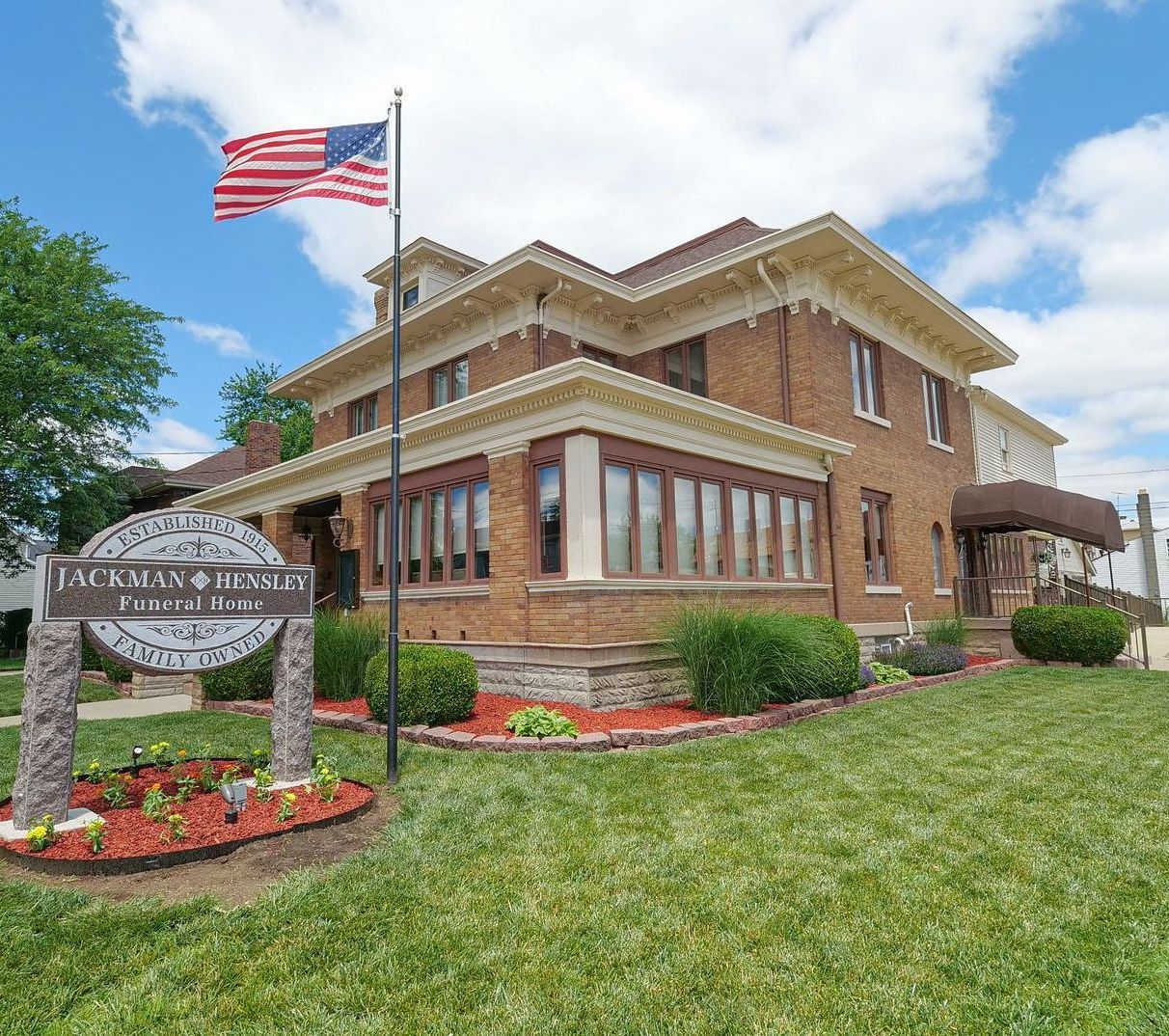 A wooden walkway leading to a gazebo overlooking a body of water at sunset.