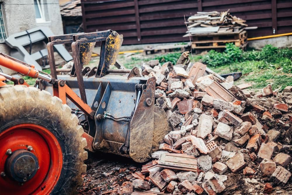 A Bulldozer Is Carrying A Pile Of Bricks In Its Bucket — Glen Tier Bobcat & Truck Hire In Cairns, QLD