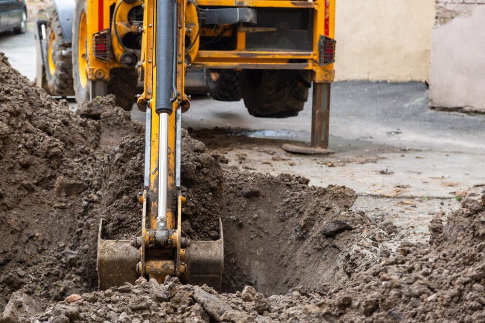 A Yellow Excavator Is Digging A Hole In The Ground — Glen Tier Bobcat & Truck Hire In Tully, QLD