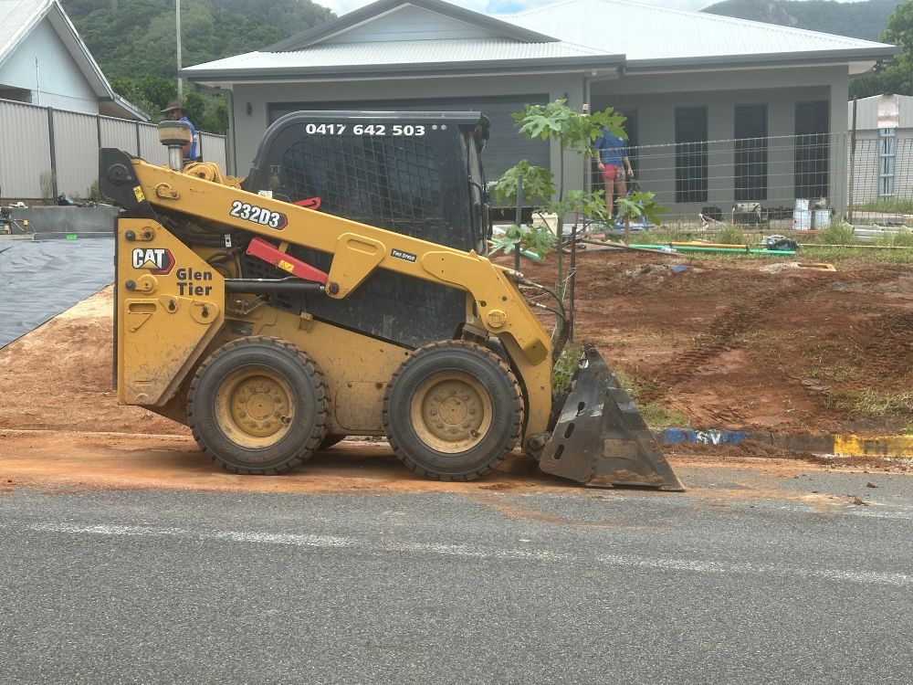 An Excavator Is Loading Dirt Into A Dump Truck At A Construction Site — Glen Tier Bobcat & Truck Hire In Woree, QLD