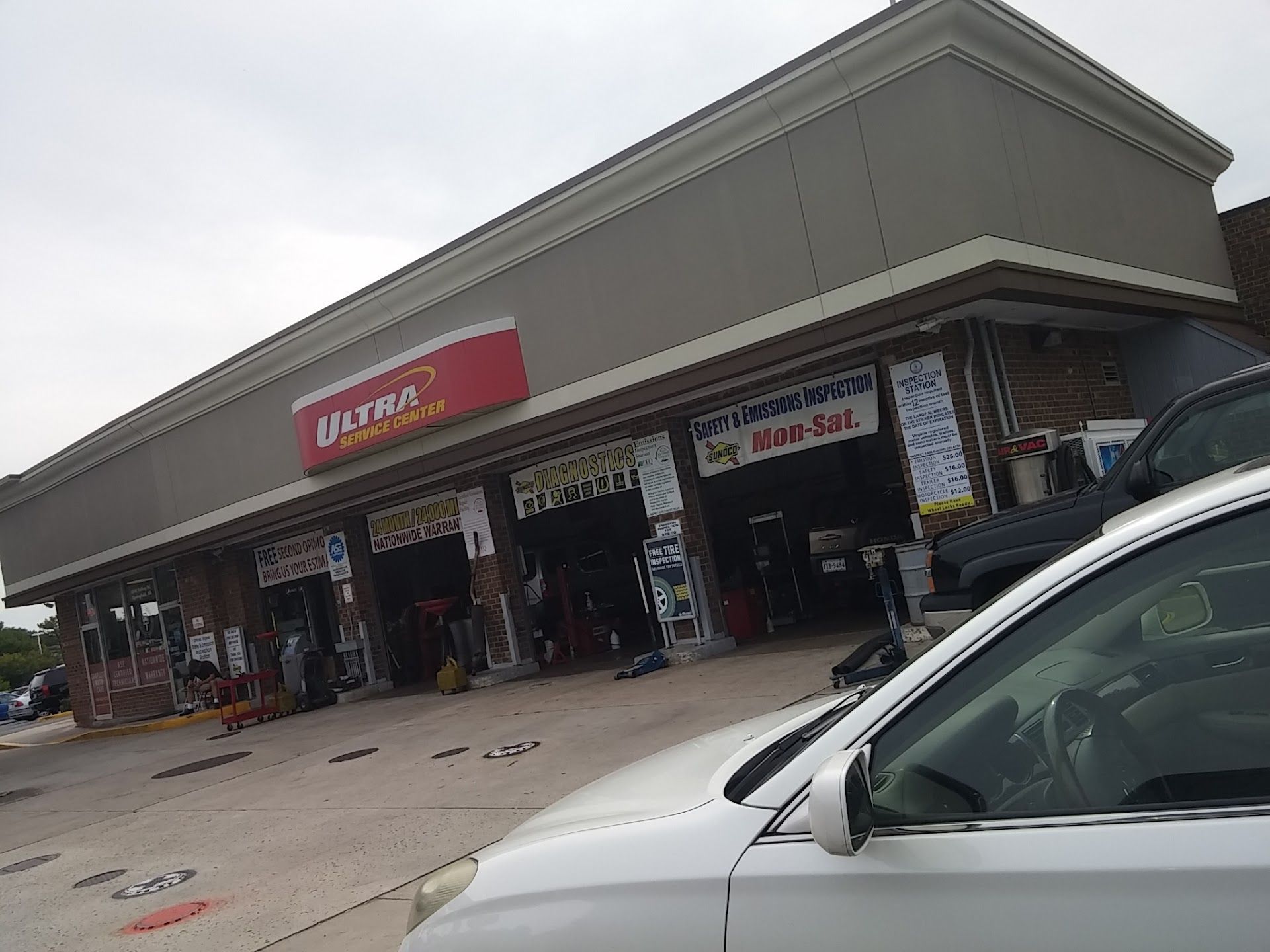 Exterior view of an auto repair shop with signage. A white car is parked in the foreground. | Saratoga Sunoco