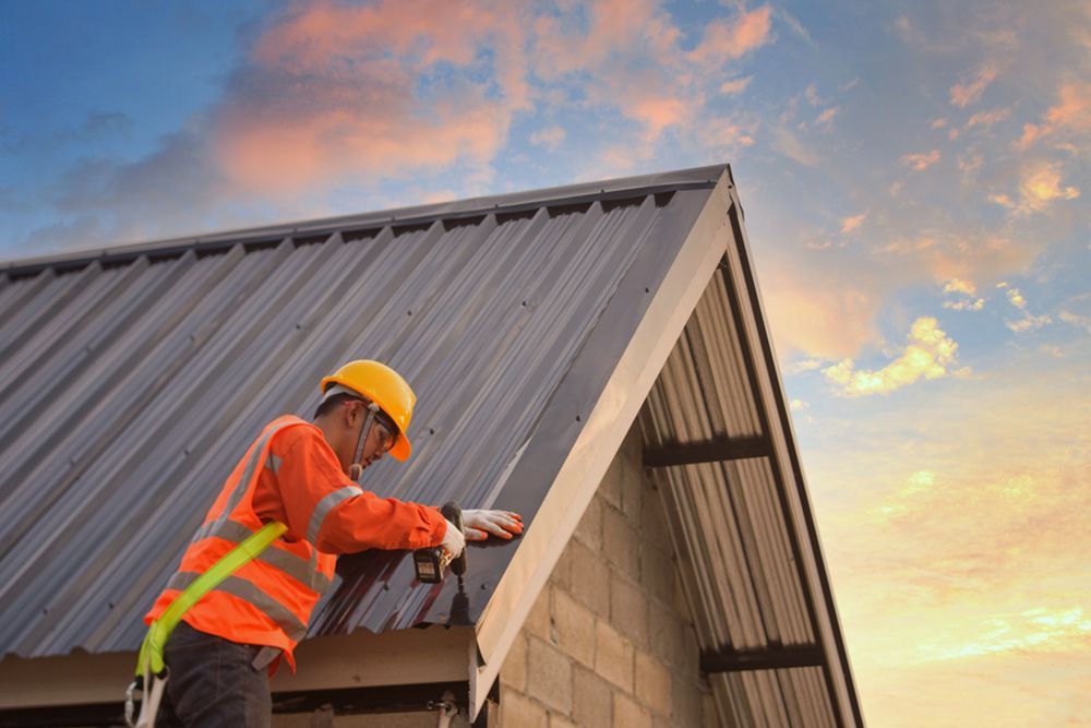 Man Installing the Roof of the House Using Automatic Driller — Builder in Deepwater, QLD