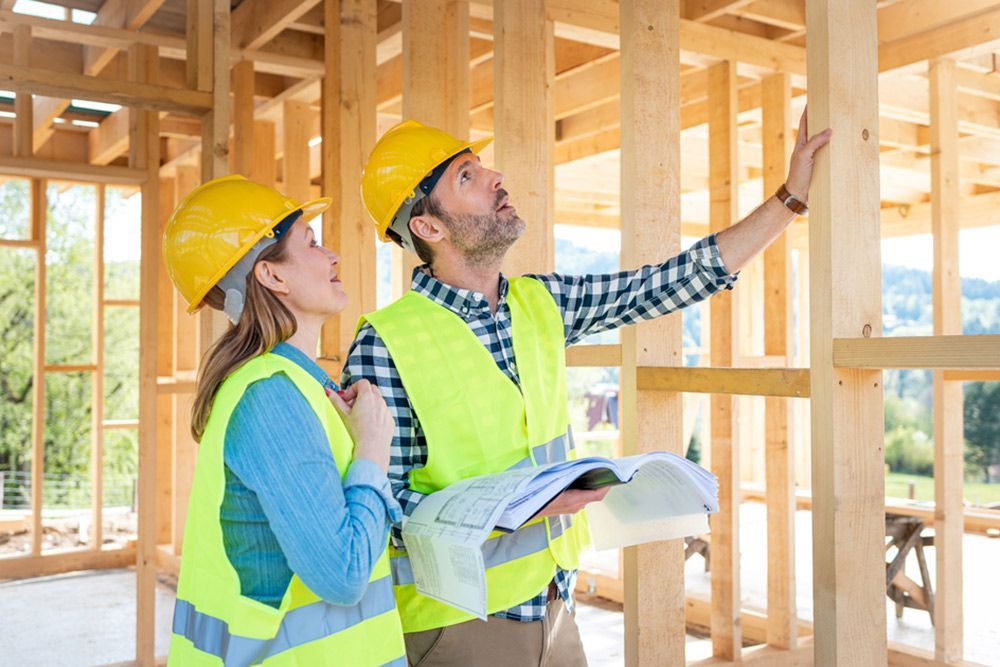 Man and Woman Looking at the House While Holding a Blueprint — Builder in Lowmead, QLD