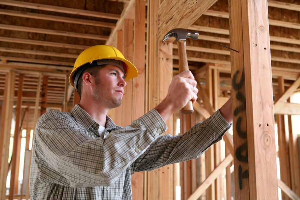 Man Using Hammer to Insert Iron Nails in the Wooden Wall Structure — Builder in Rosedale, QLD