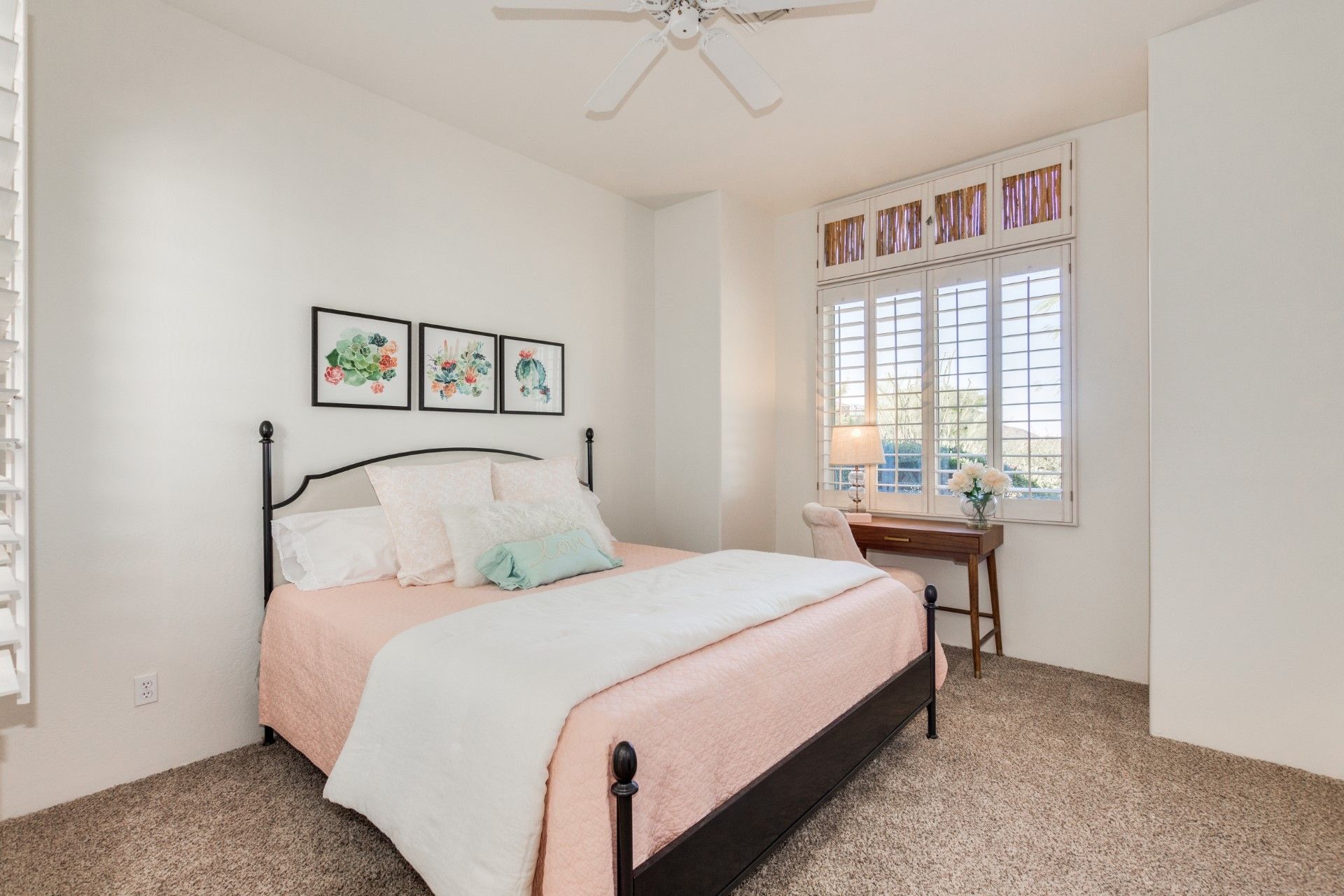 A bedroom with a bed , desk and a ceiling fan.
