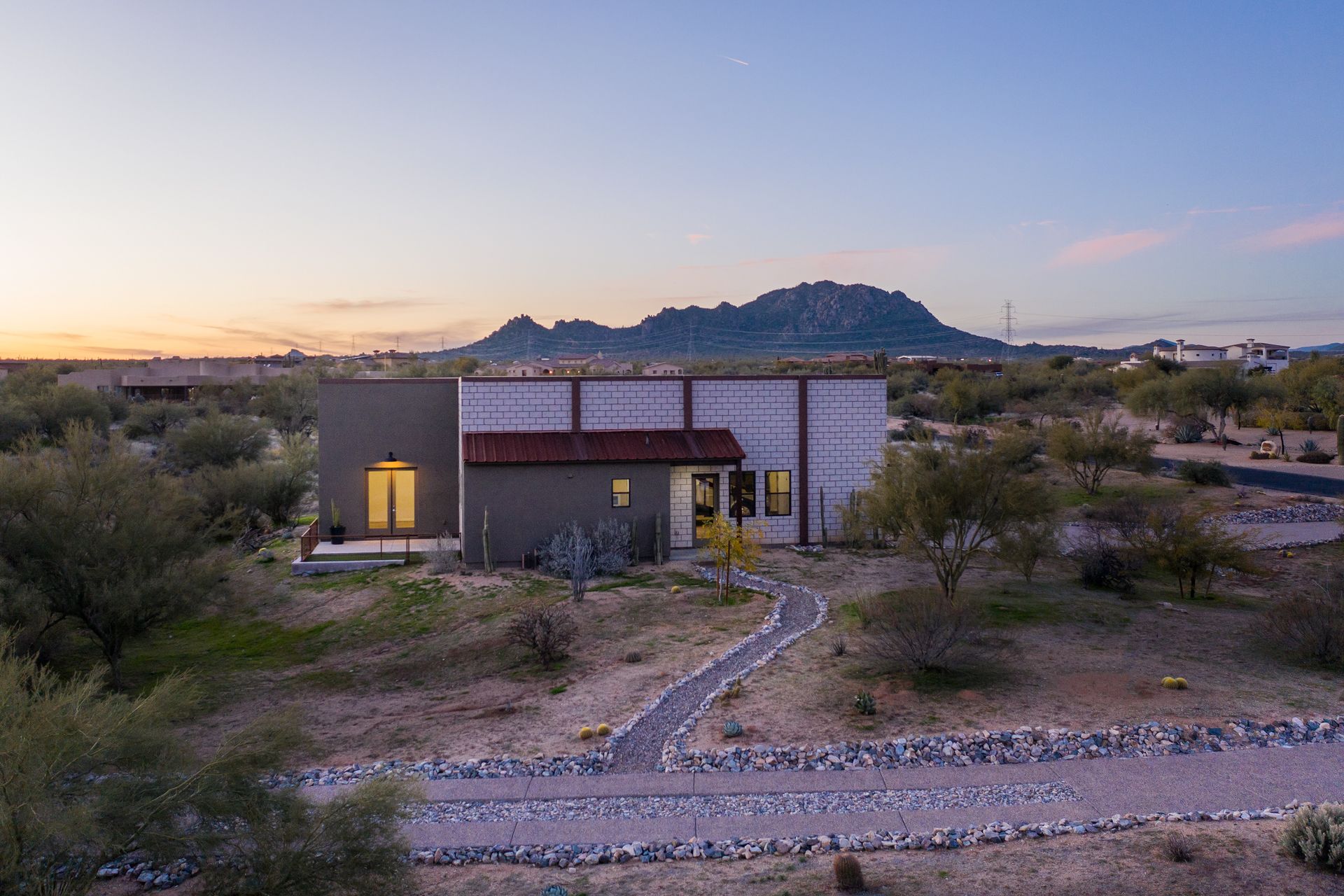 An aerial view of a house in the desert with a mountain in the background.