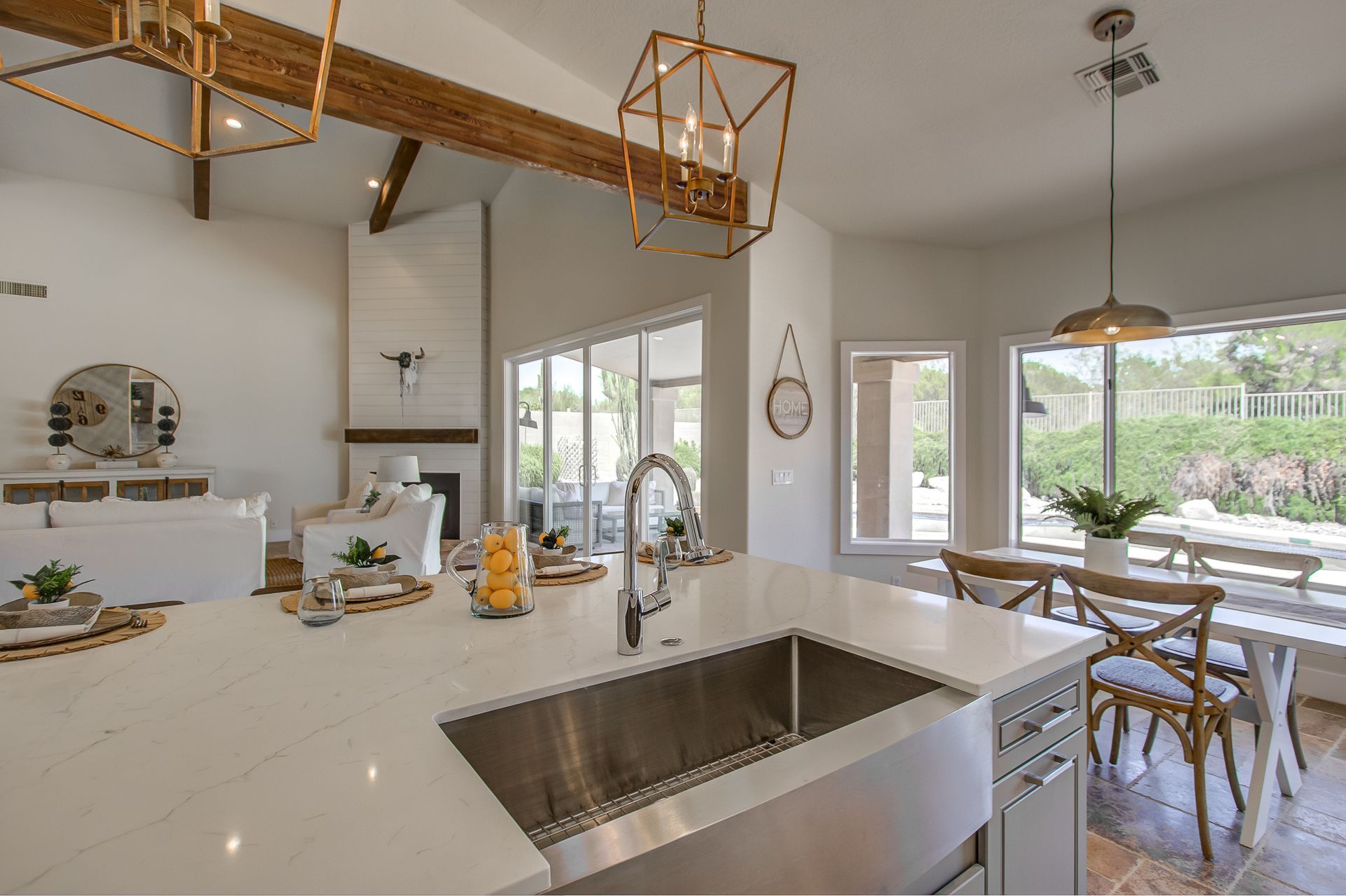 A kitchen with a stainless steel sink and white counter tops.
