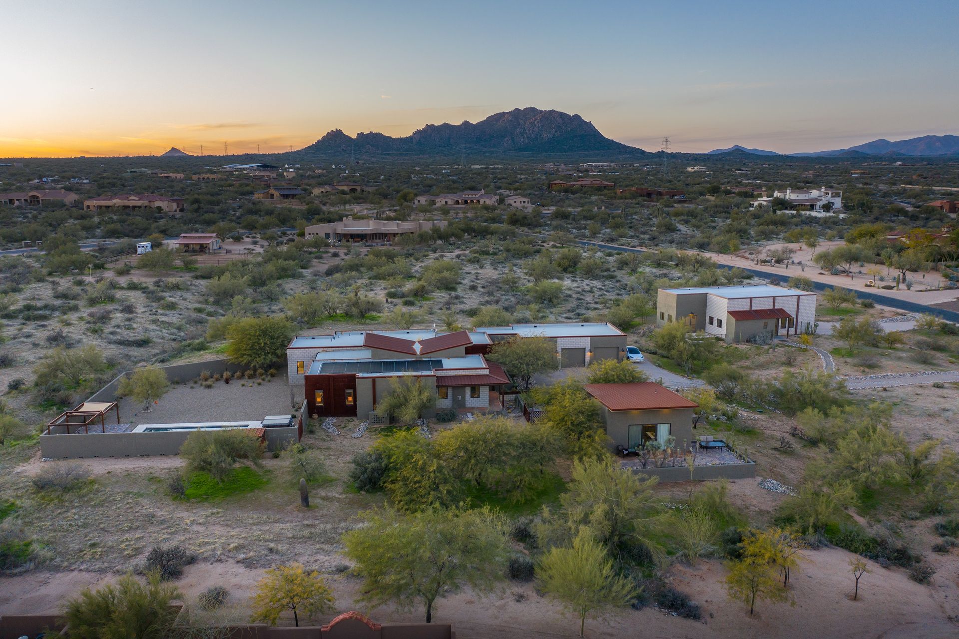 An aerial view of a house in the desert with a mountain in the background.