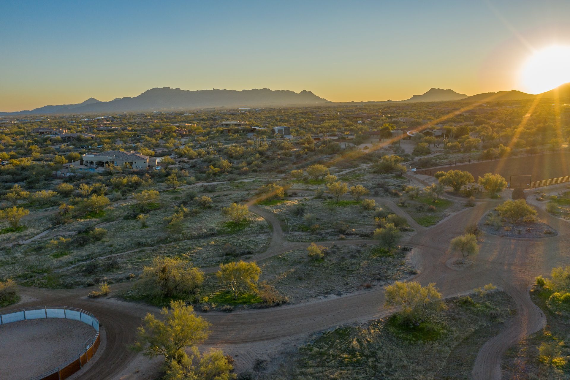 An aerial view of a desert landscape with a sunset in the background.