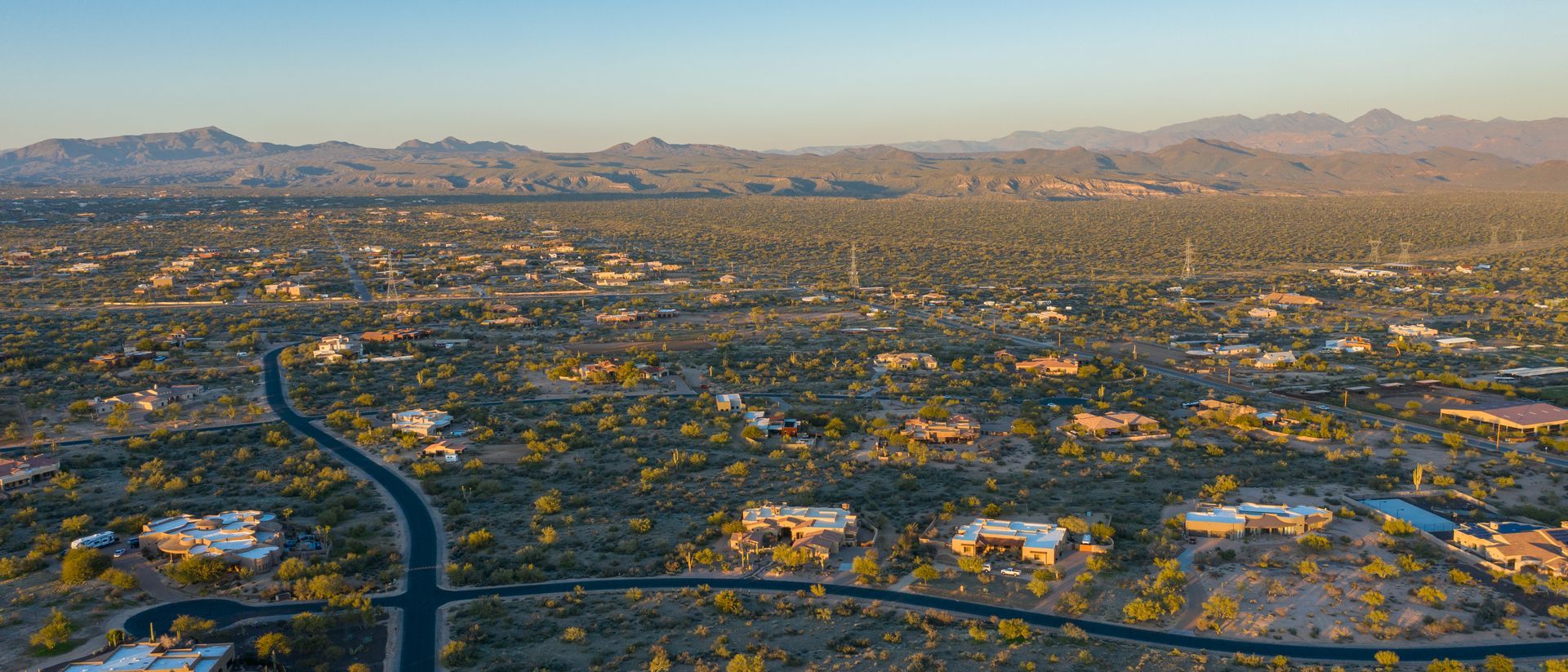 An aerial view of a residential area in the desert with mountains in the background.