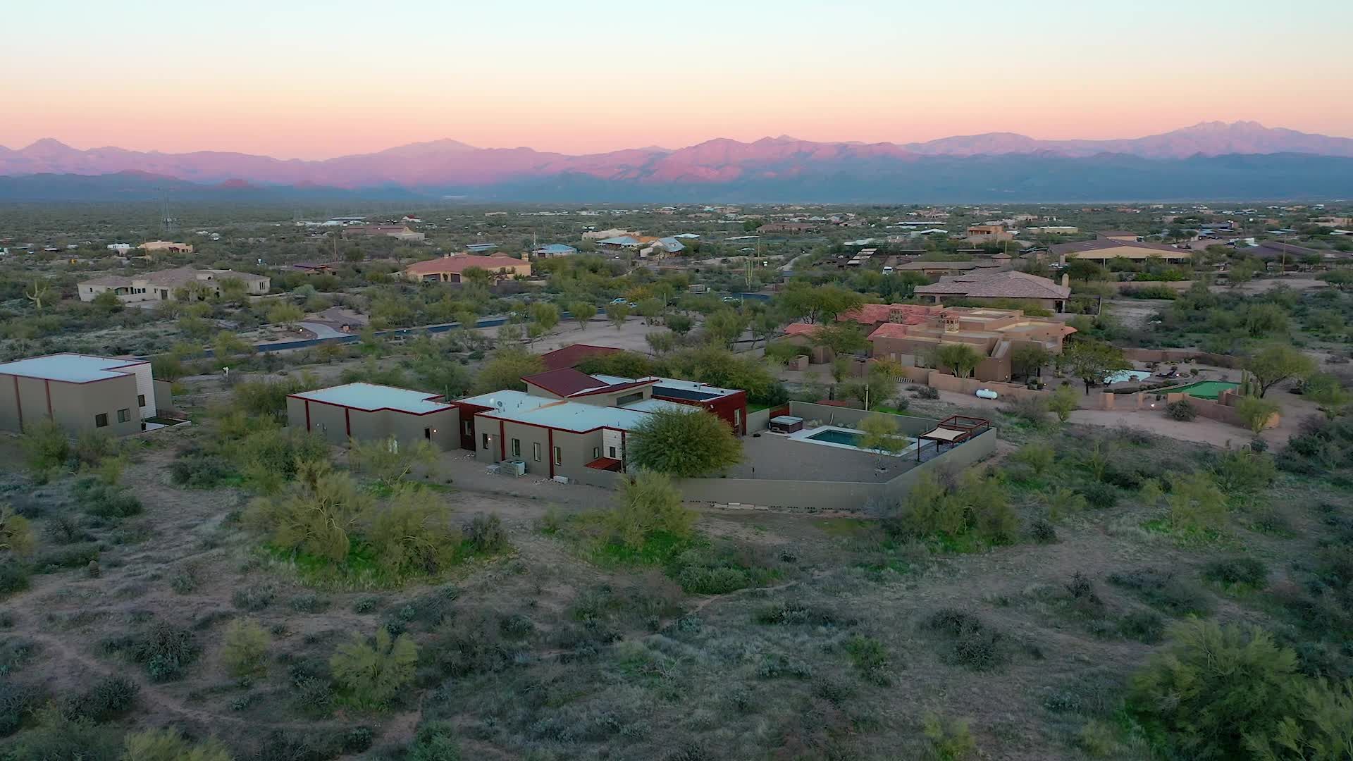 An aerial view of a residential area with mountains in the background at sunset.