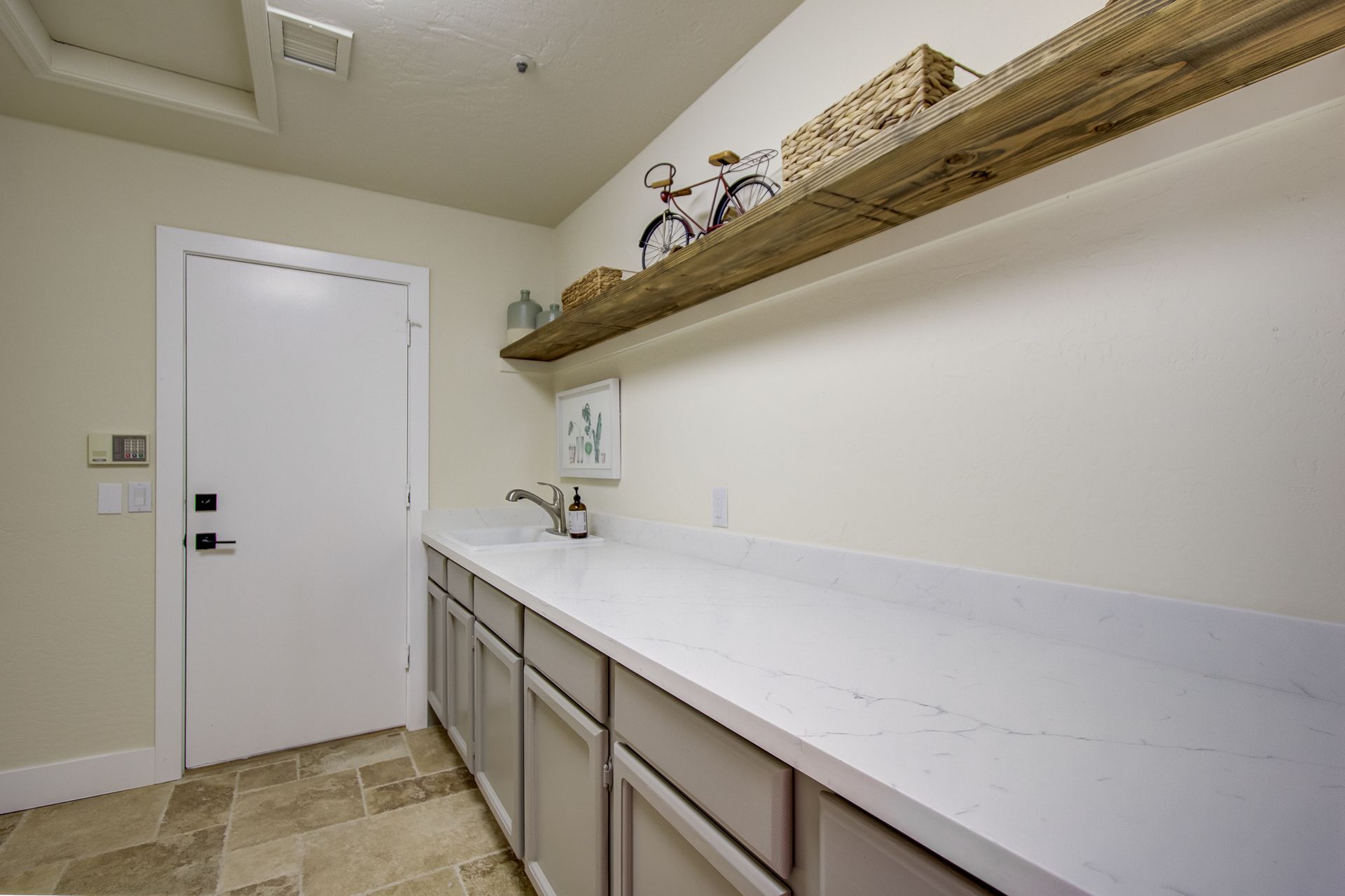 A laundry room with a sink and a shelf with bicycles on it.