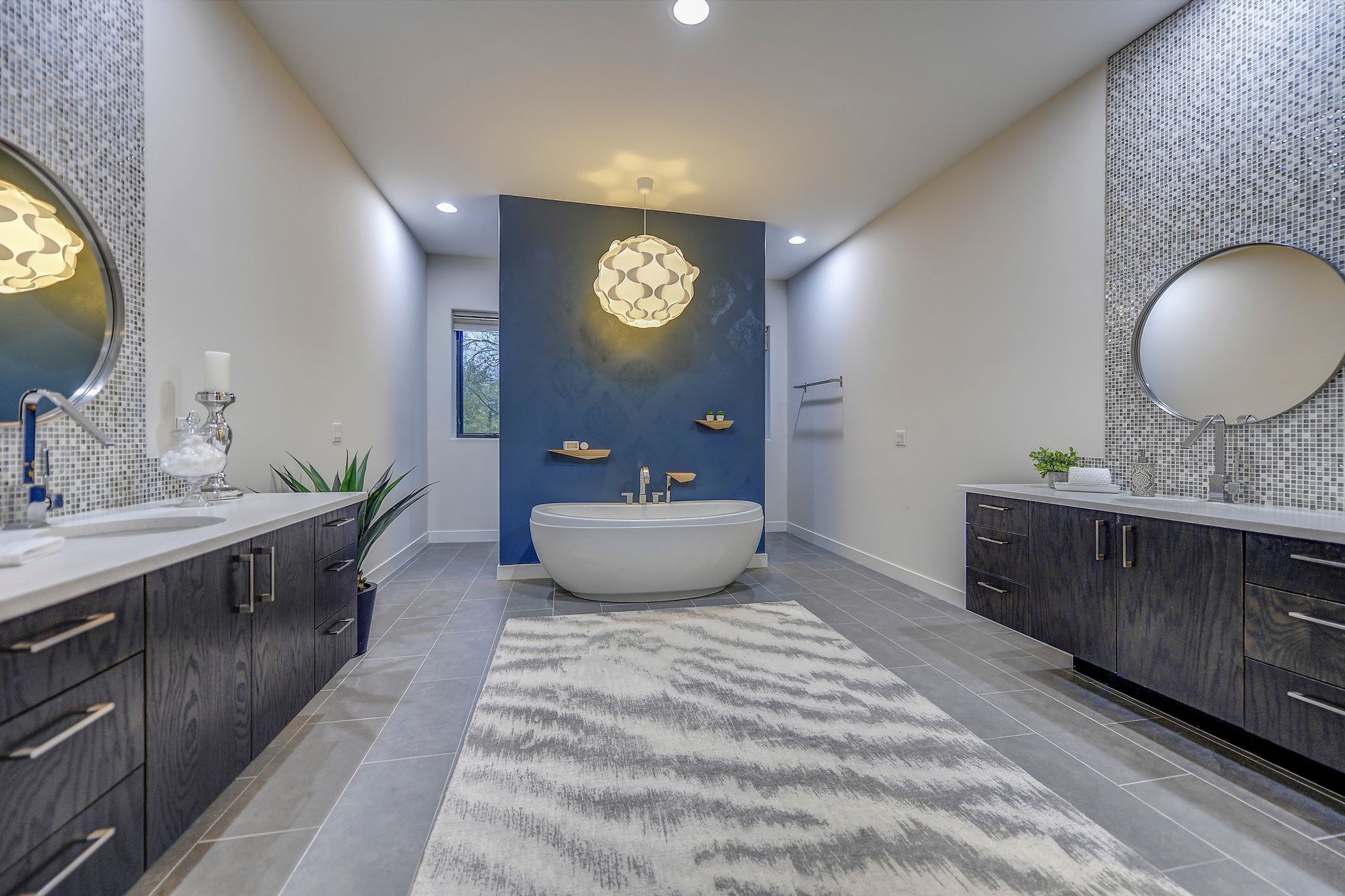A bathroom with a tub , sinks , mirrors and a rug.