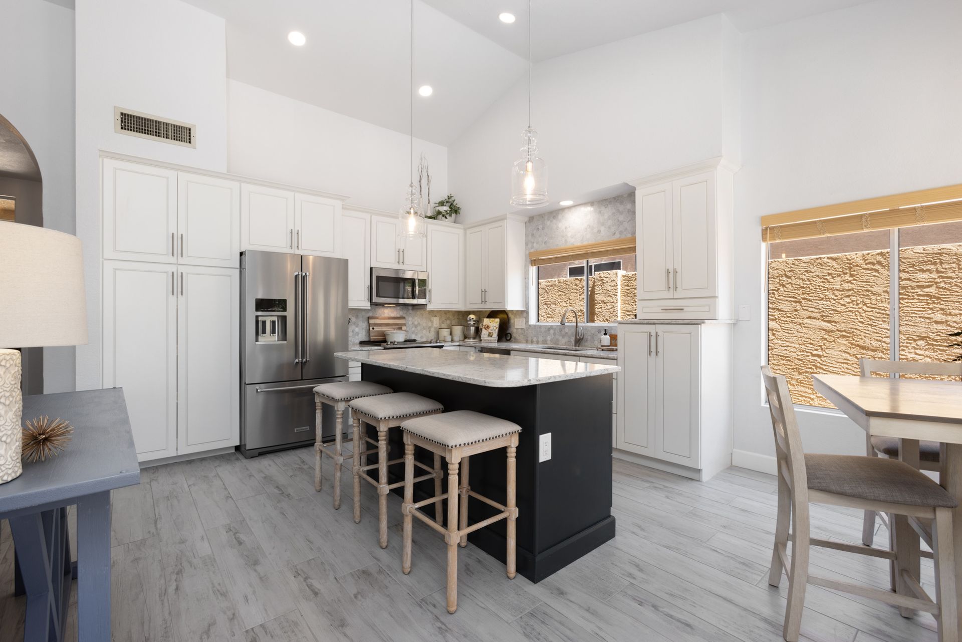 A kitchen with white cabinets , stainless steel appliances and a large island.