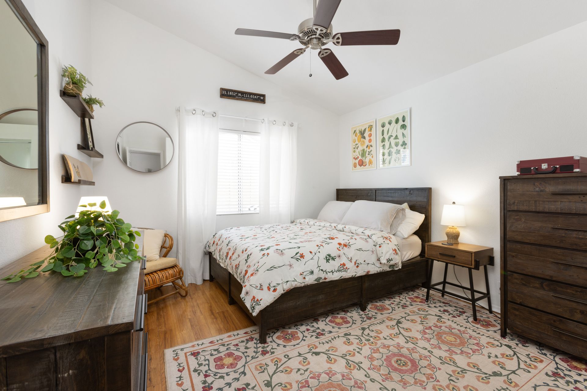 A bedroom with a bed , dresser , mirror and ceiling fan.