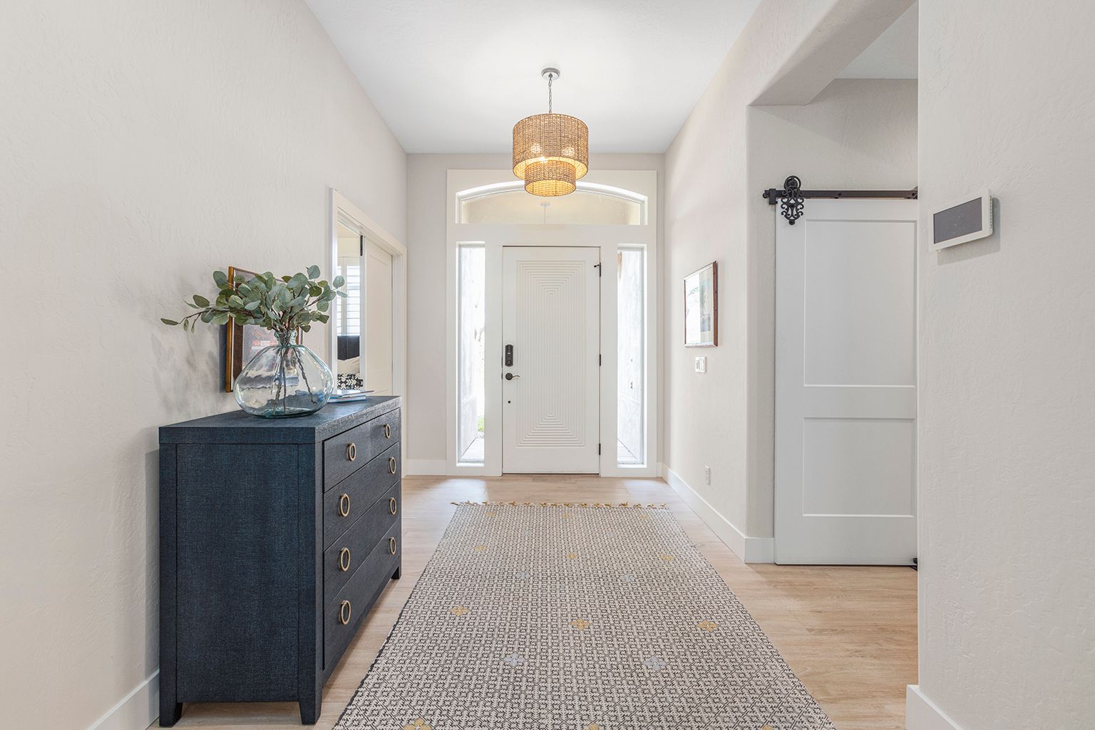 A hallway in a house with a dresser and a rug.