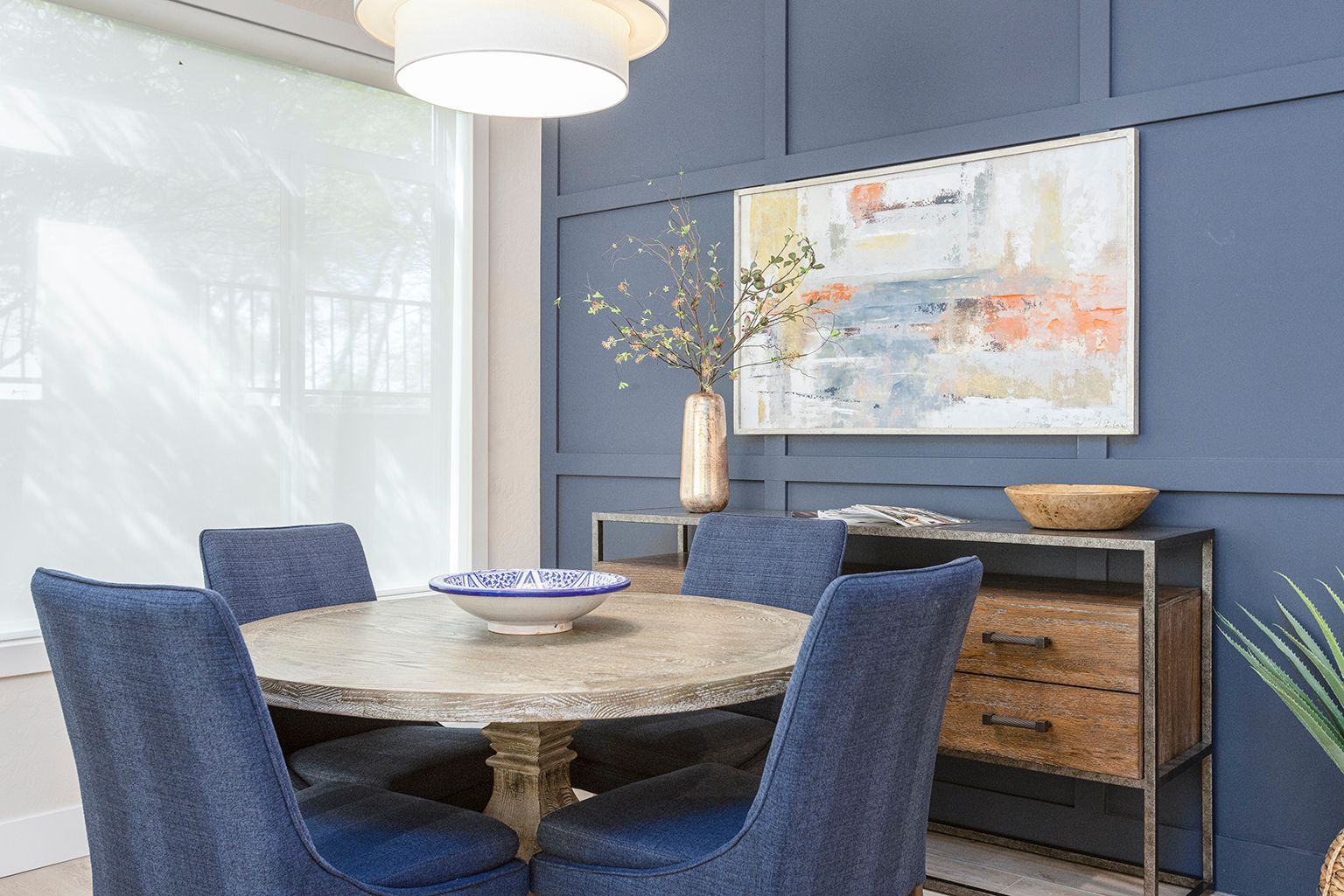 A dining room with a round table and blue chairs.