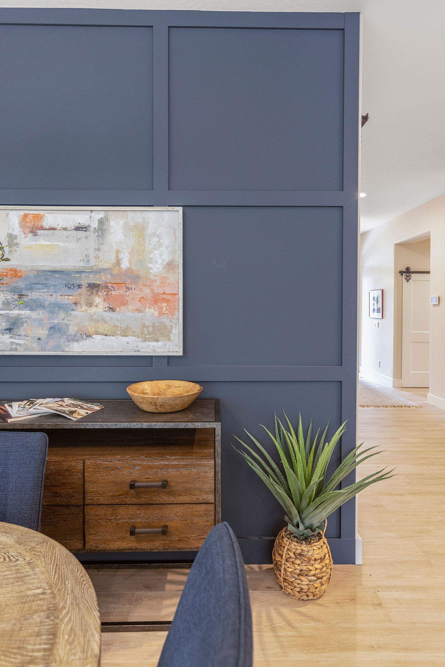 A living room with a blue wall and a painting on the wall.