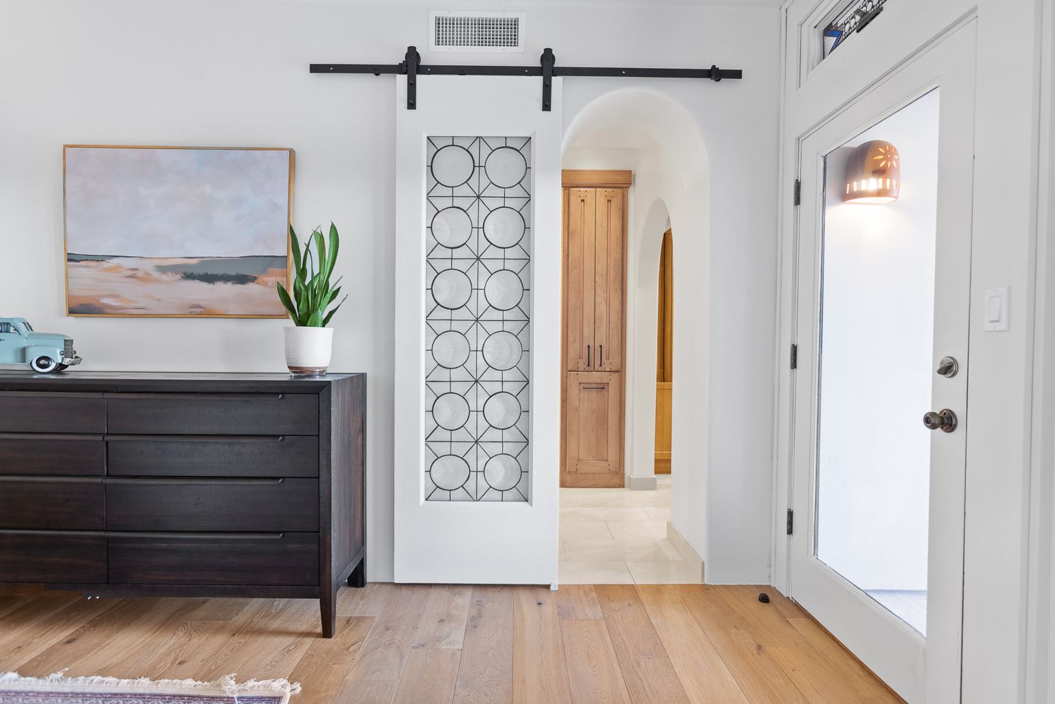 A living room with a sliding barn door and a dresser.