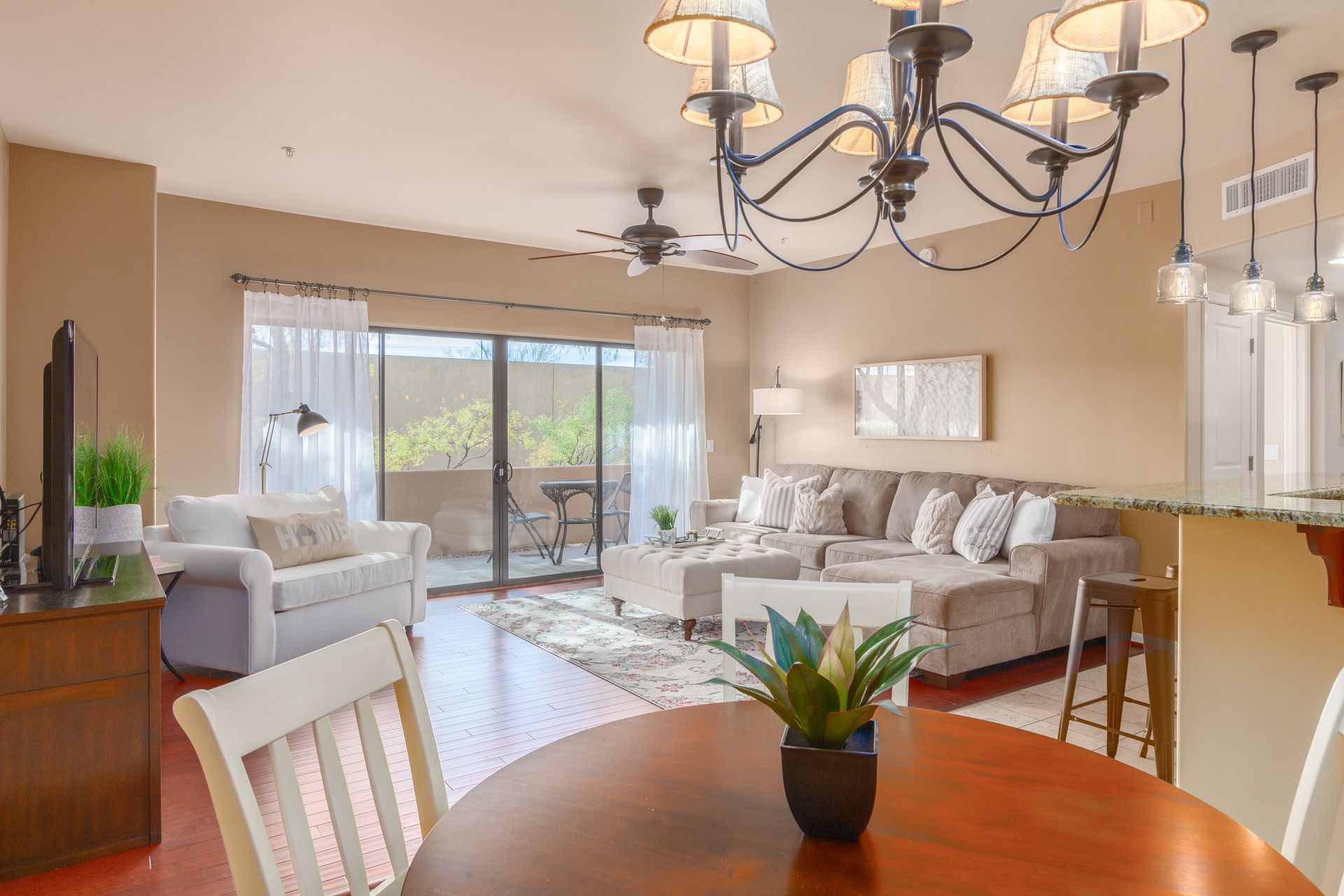 A living room with a dining table , chairs , a couch and a chandelier.