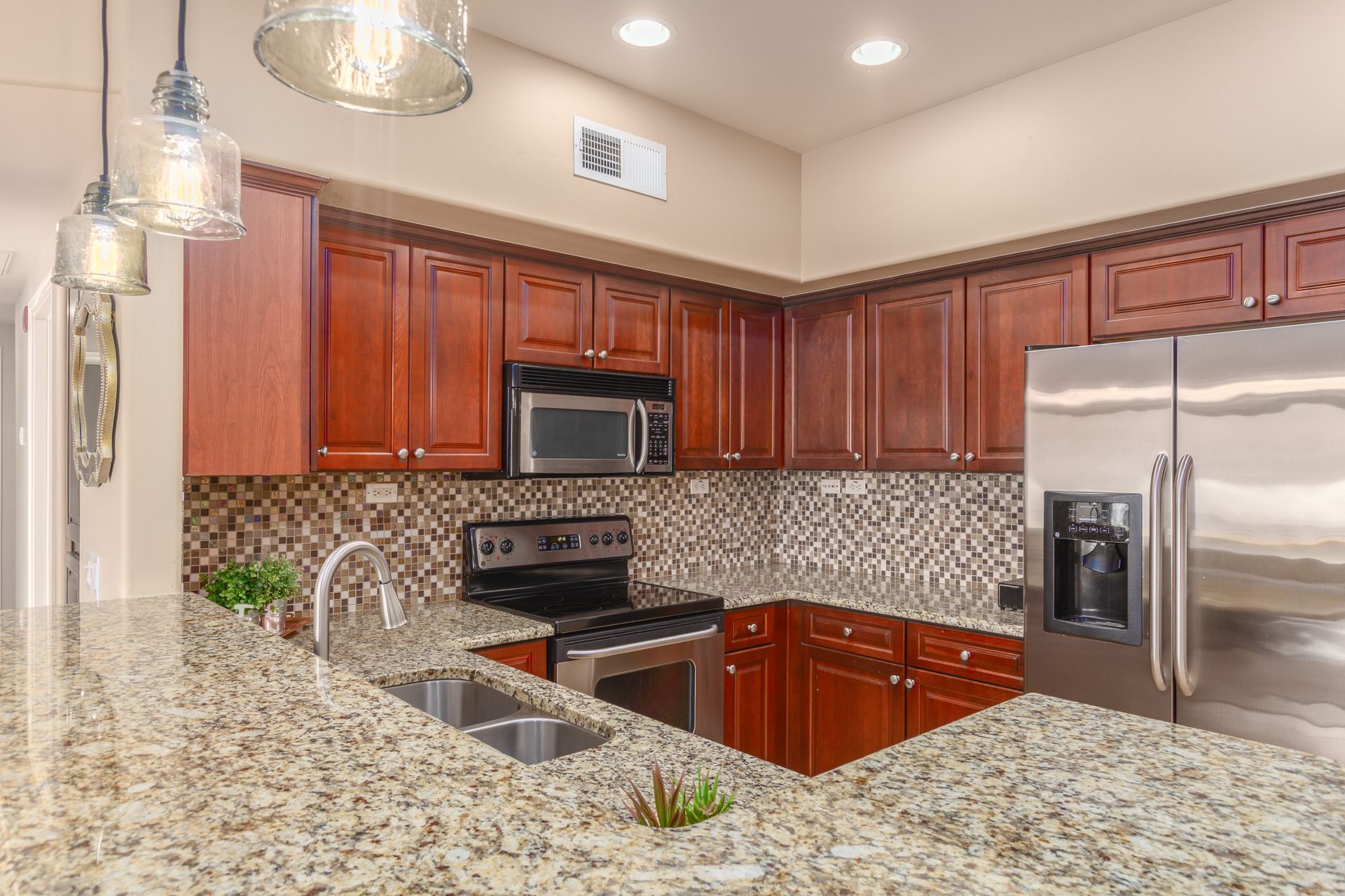 A kitchen with granite counter tops , stainless steel appliances , and wooden cabinets.