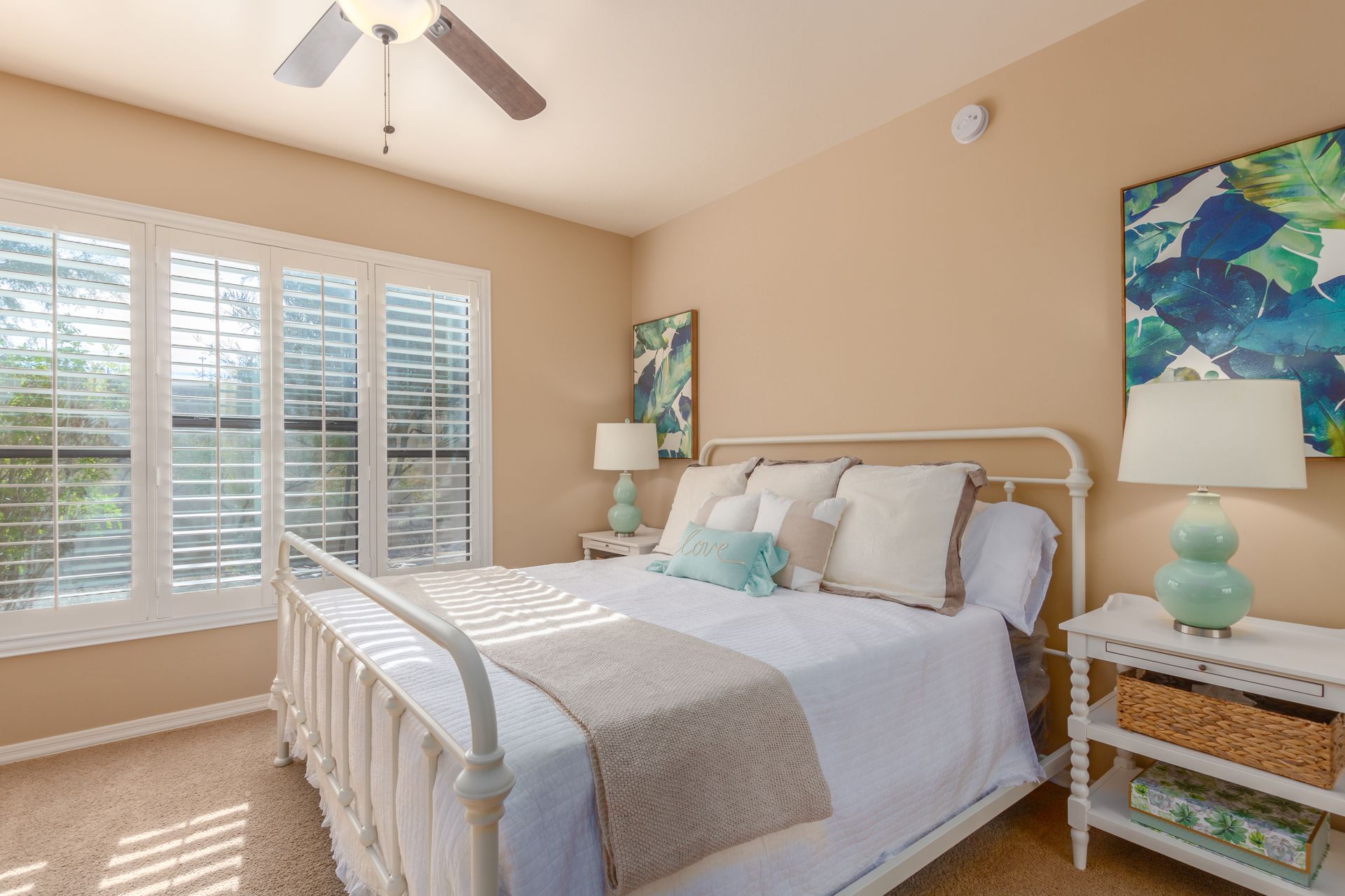 A bedroom with a bed , lamps , and a ceiling fan.