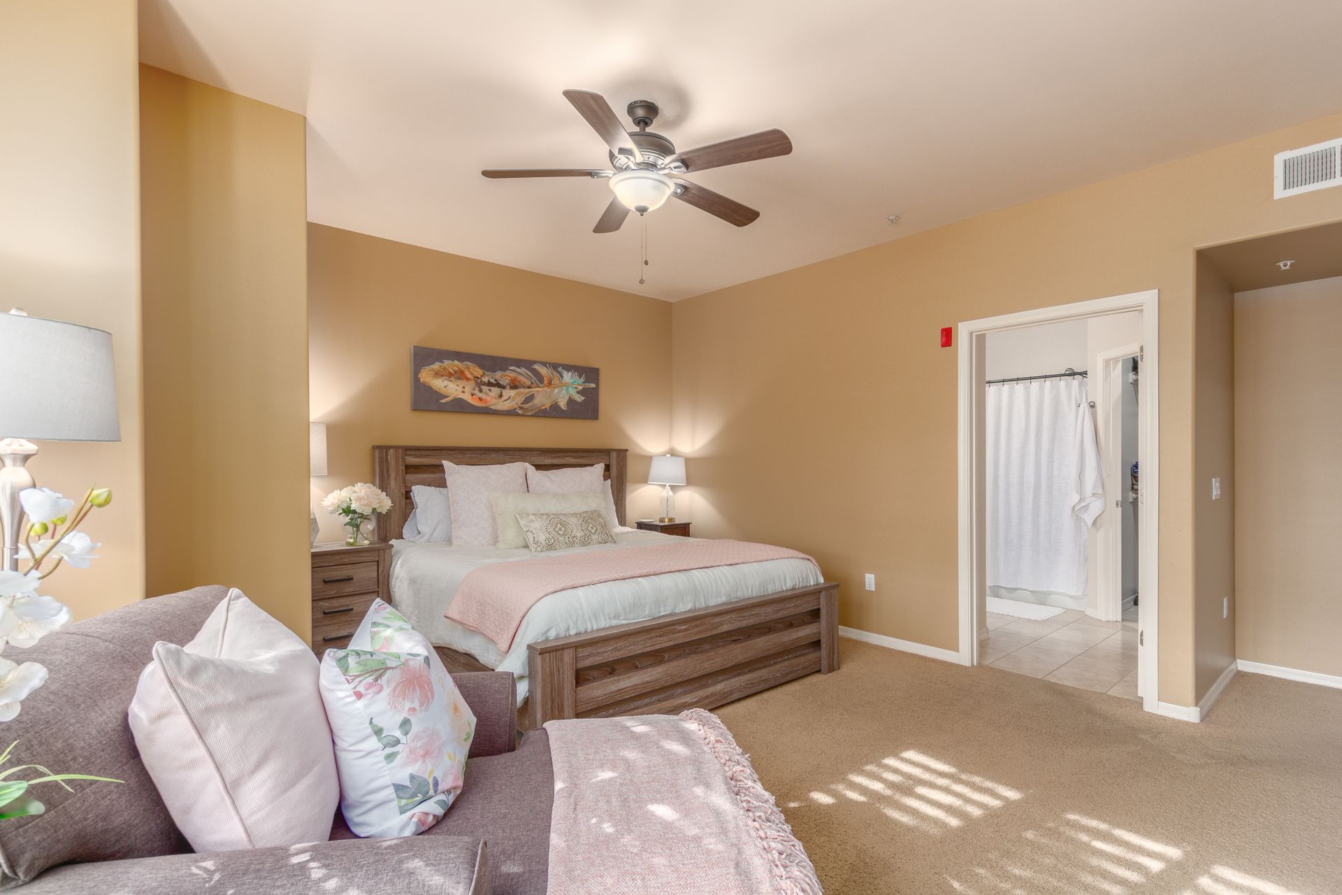 A bedroom with a king size bed , a couch , and a ceiling fan.