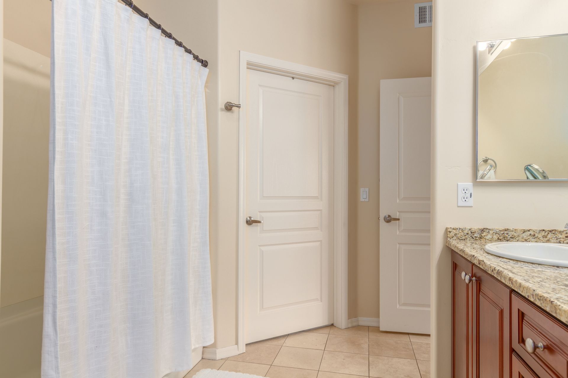 A bathroom with a shower curtain , sink and mirror.