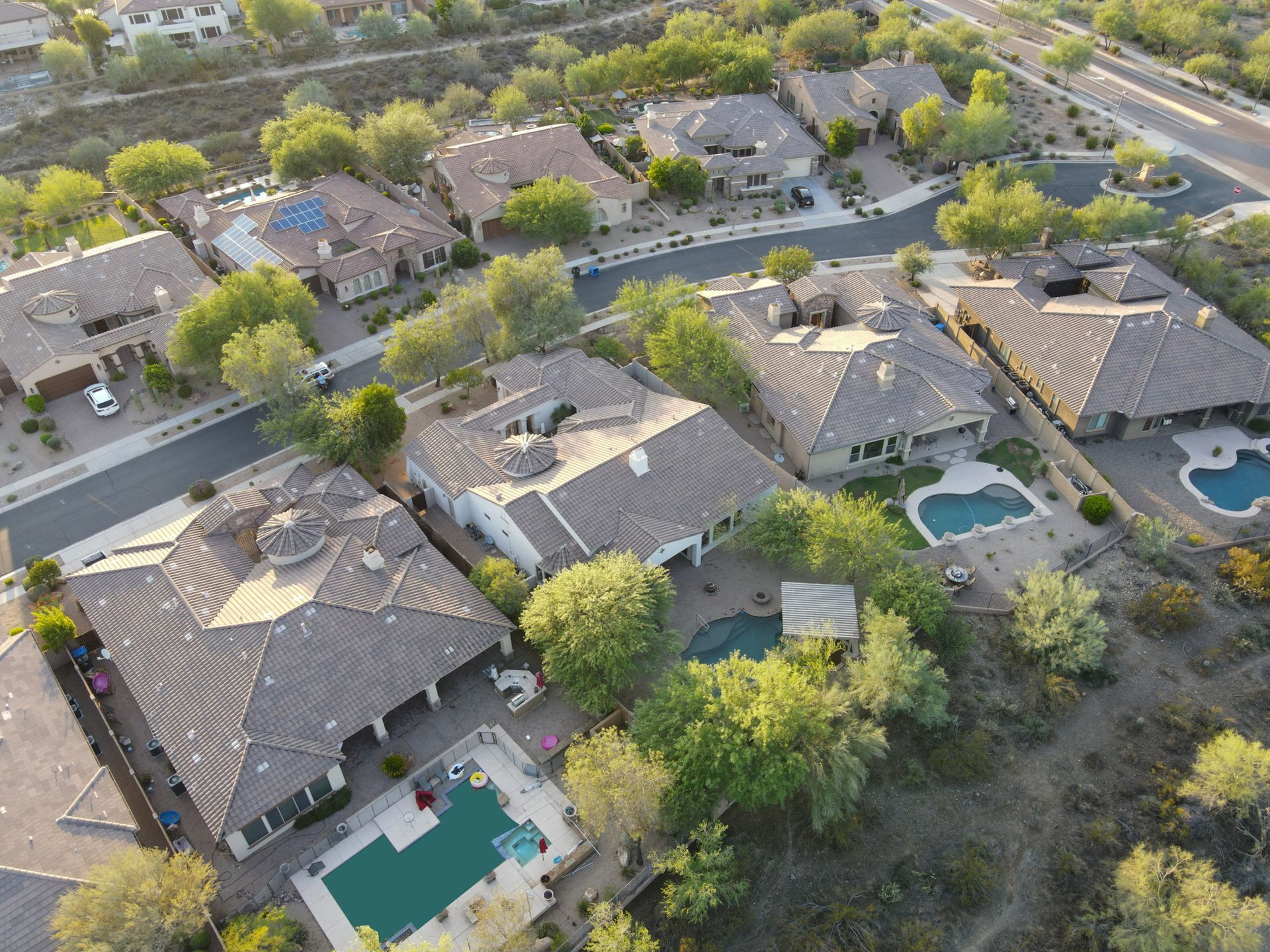 An aerial view of a residential area with lots of houses and pools.