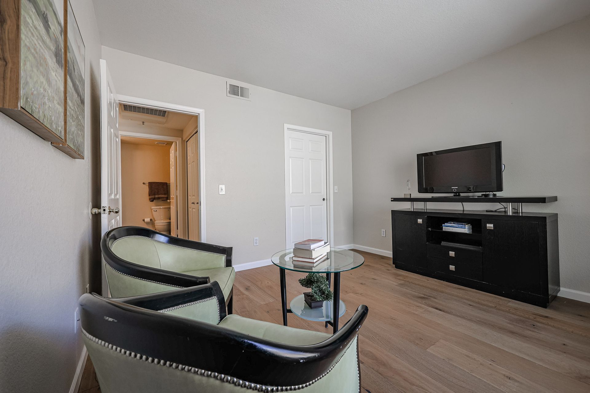 A living room with two chairs , a coffee table , and a flat screen tv.