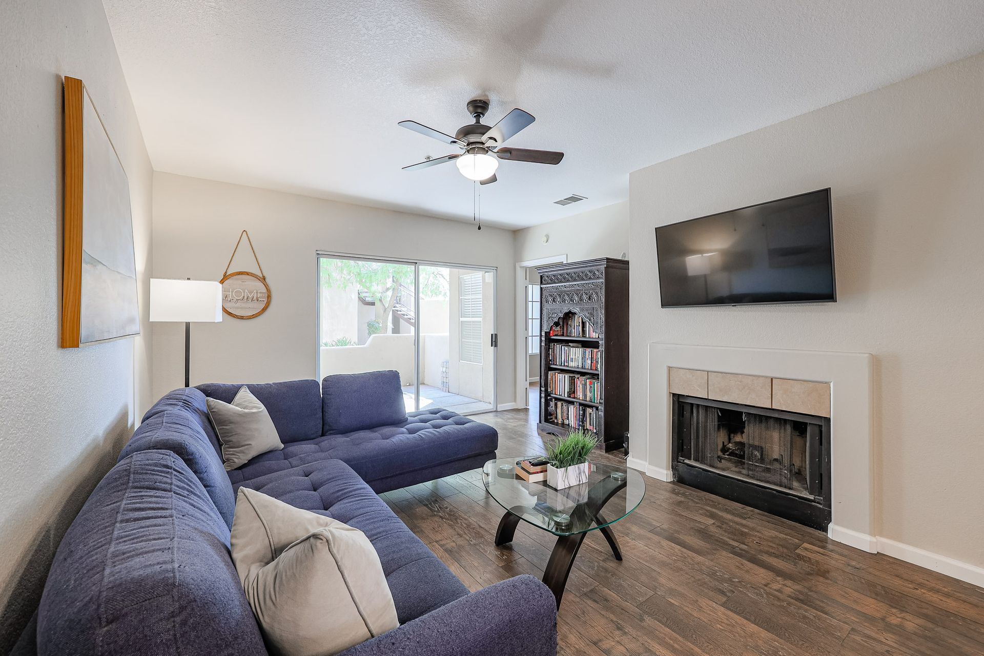 A living room with a couch , fireplace , television and ceiling fan.