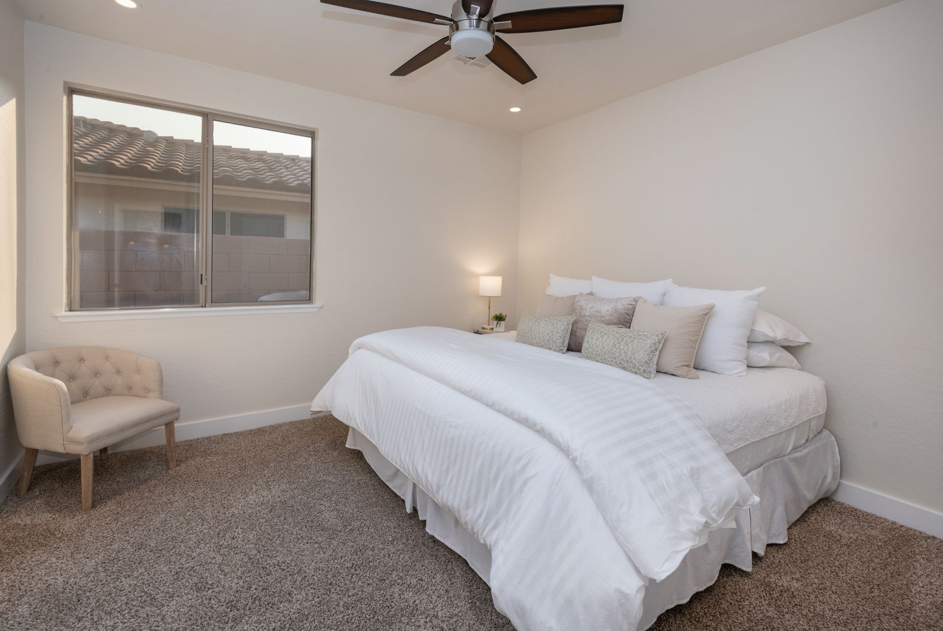 A bedroom with a bed , chair and ceiling fan.