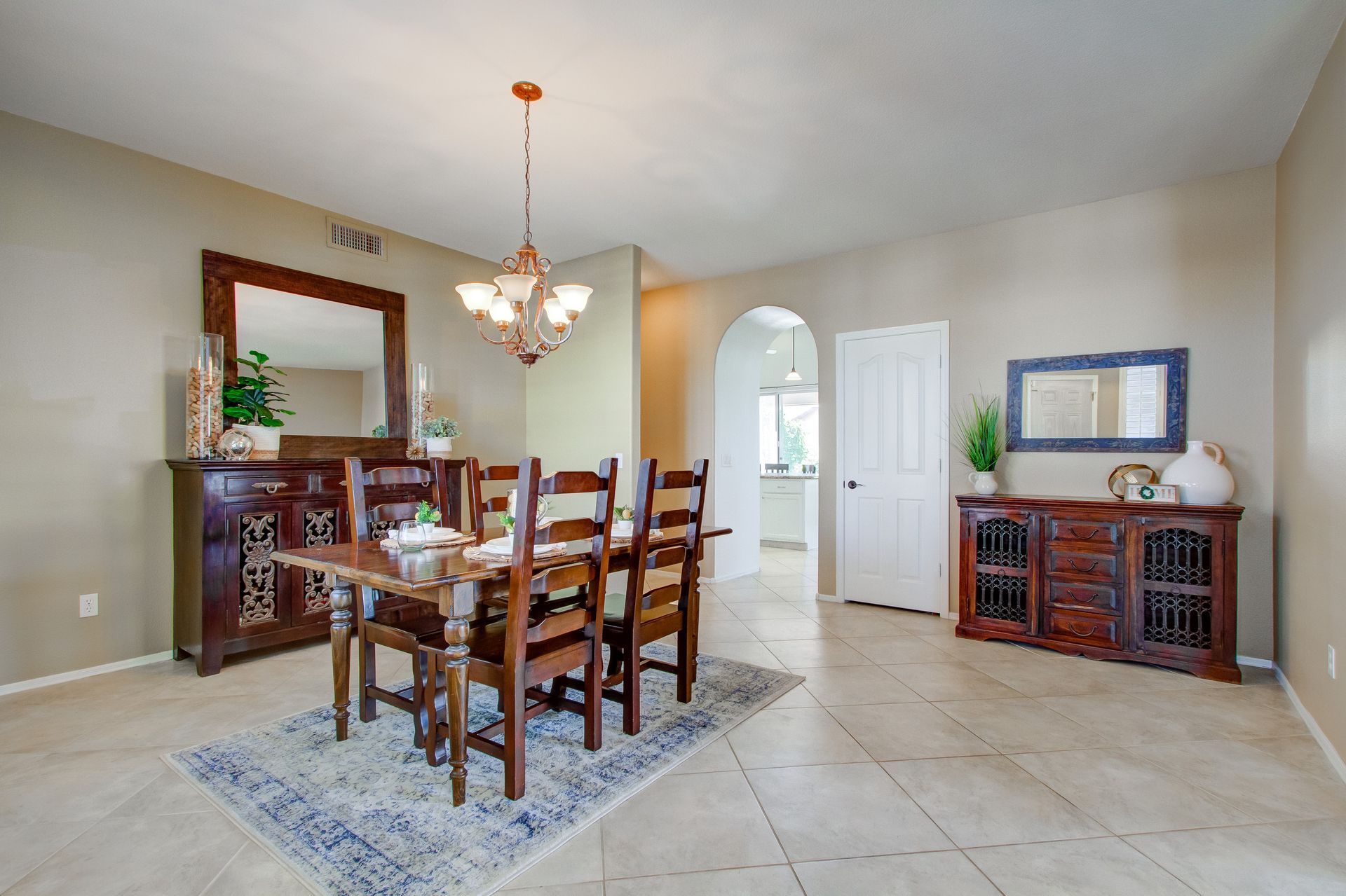 A dining room with a table and chairs and a mirror.