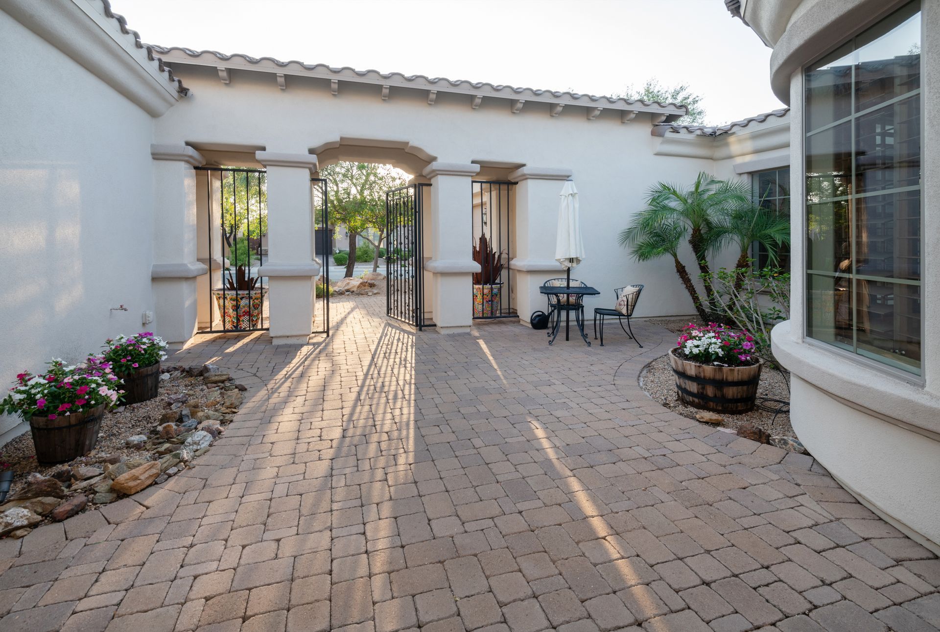 A brick walkway leading to a patio with a table and chairs