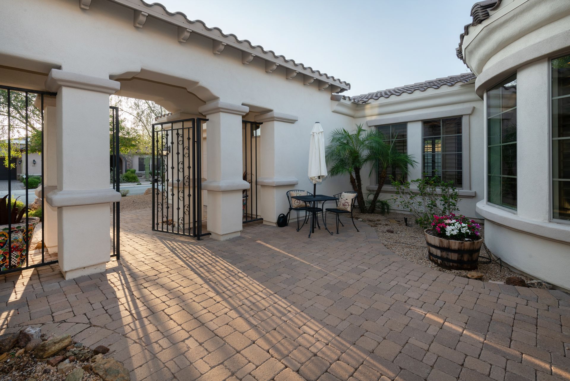 A patio with a table and chairs in front of a white building