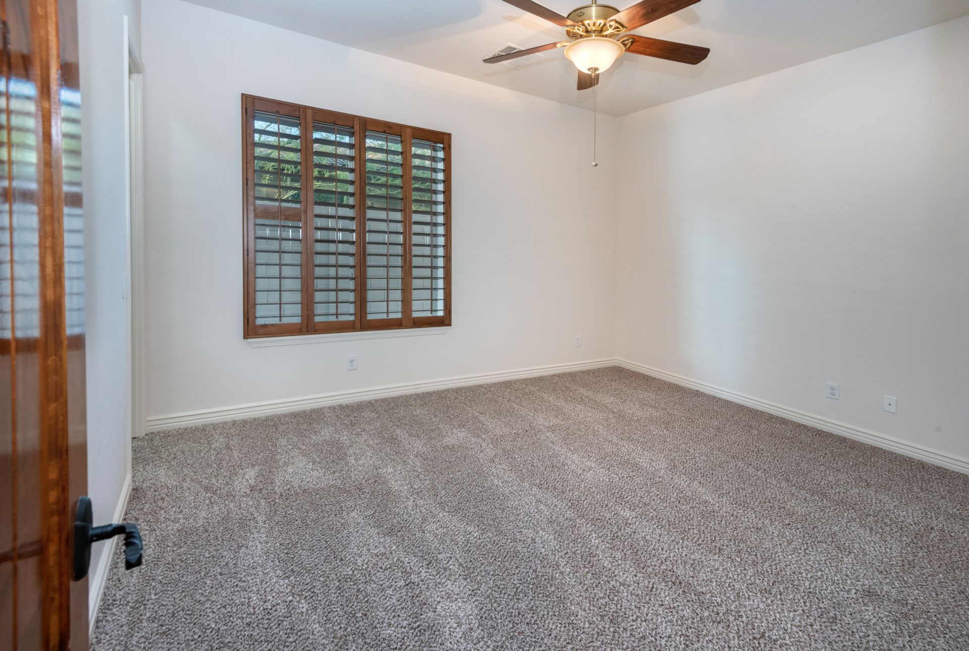 An empty bedroom with a ceiling fan and a window.