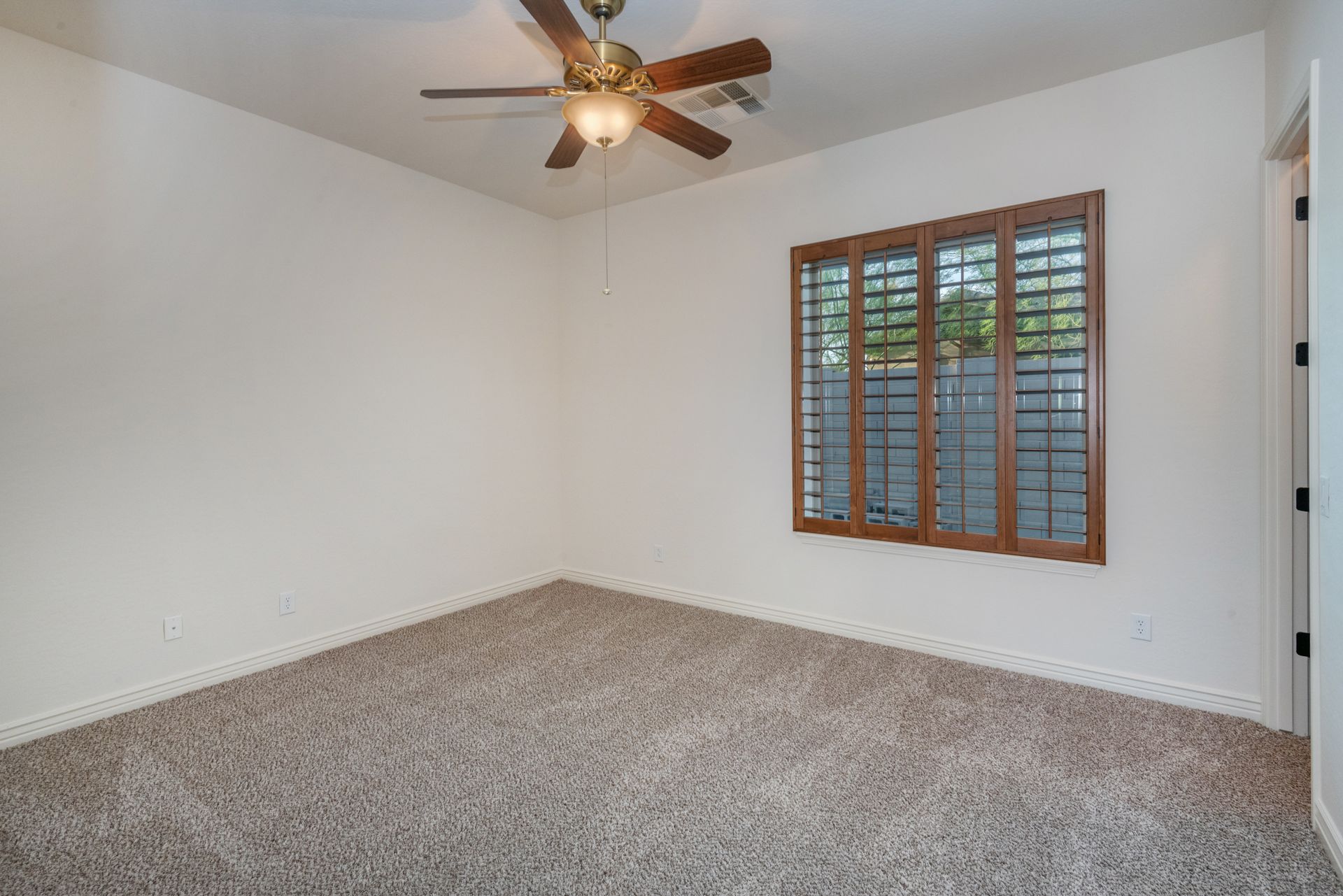 An empty bedroom with a ceiling fan and a window.