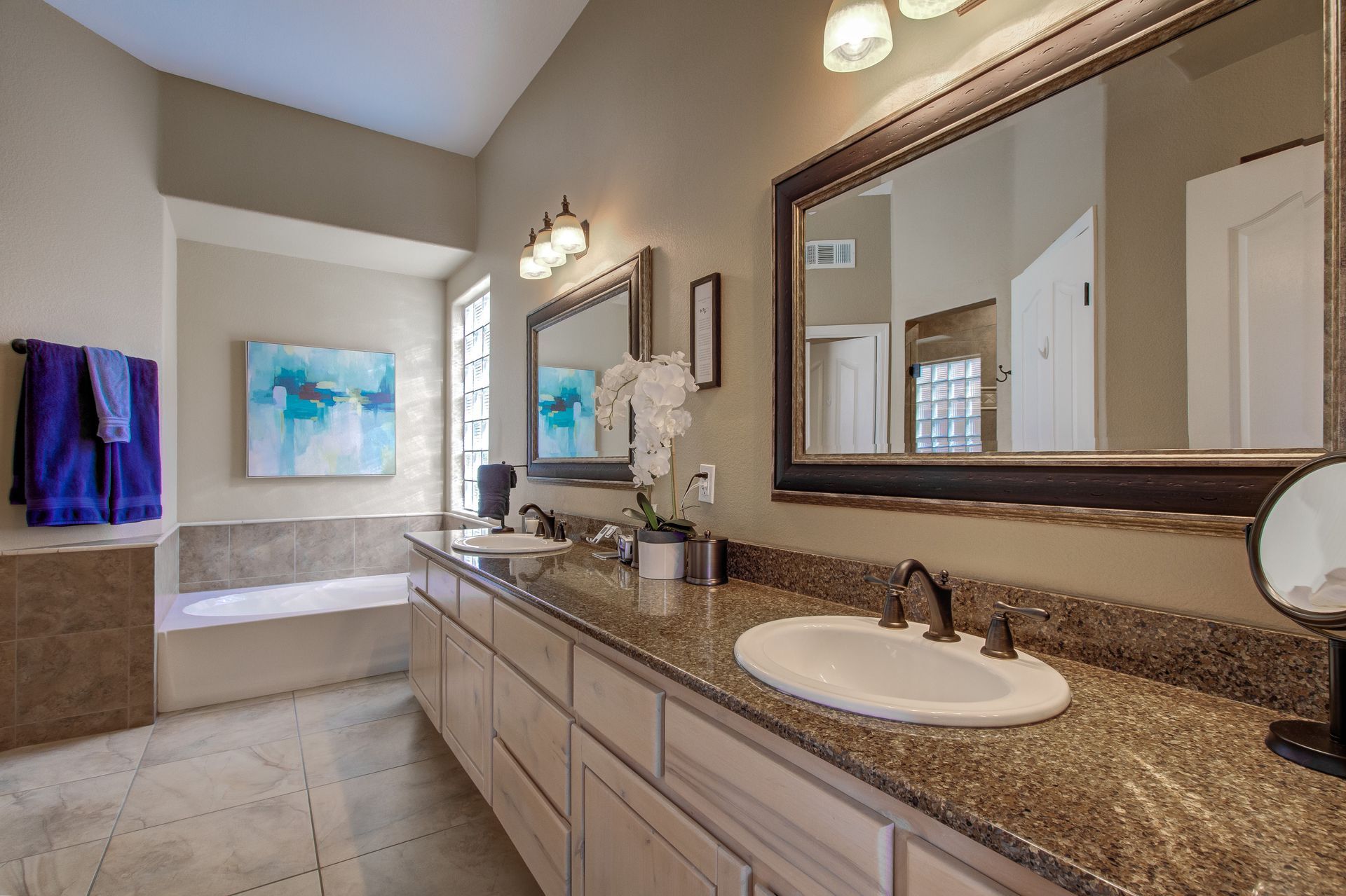 A bathroom with two sinks , two mirrors and a bathtub.