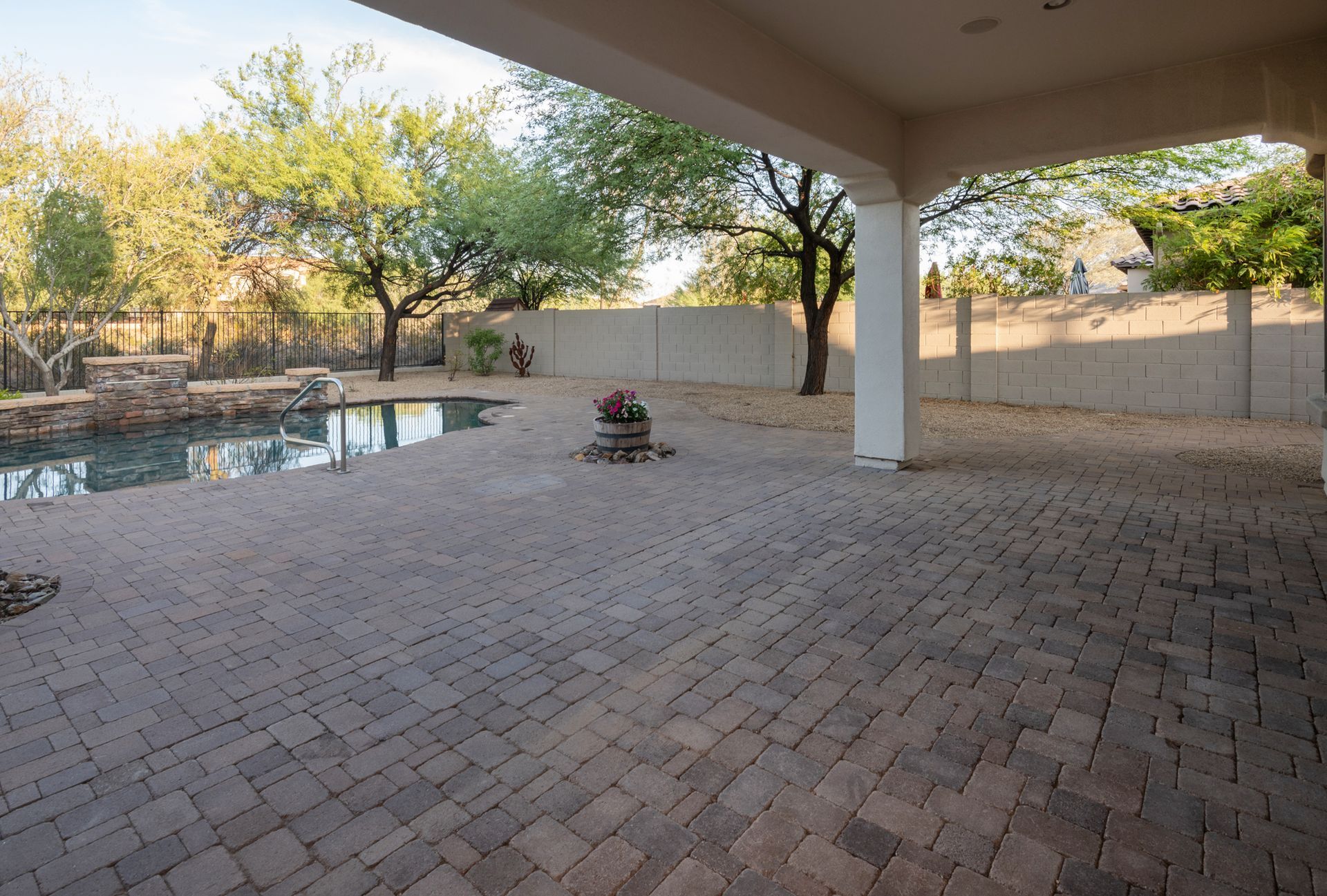 An empty patio with a swimming pool in the background