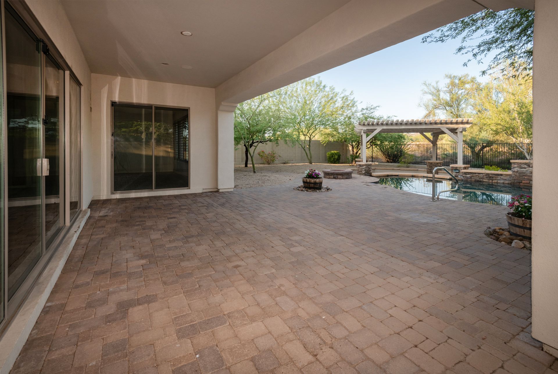 An empty patio with a pool and a pergola