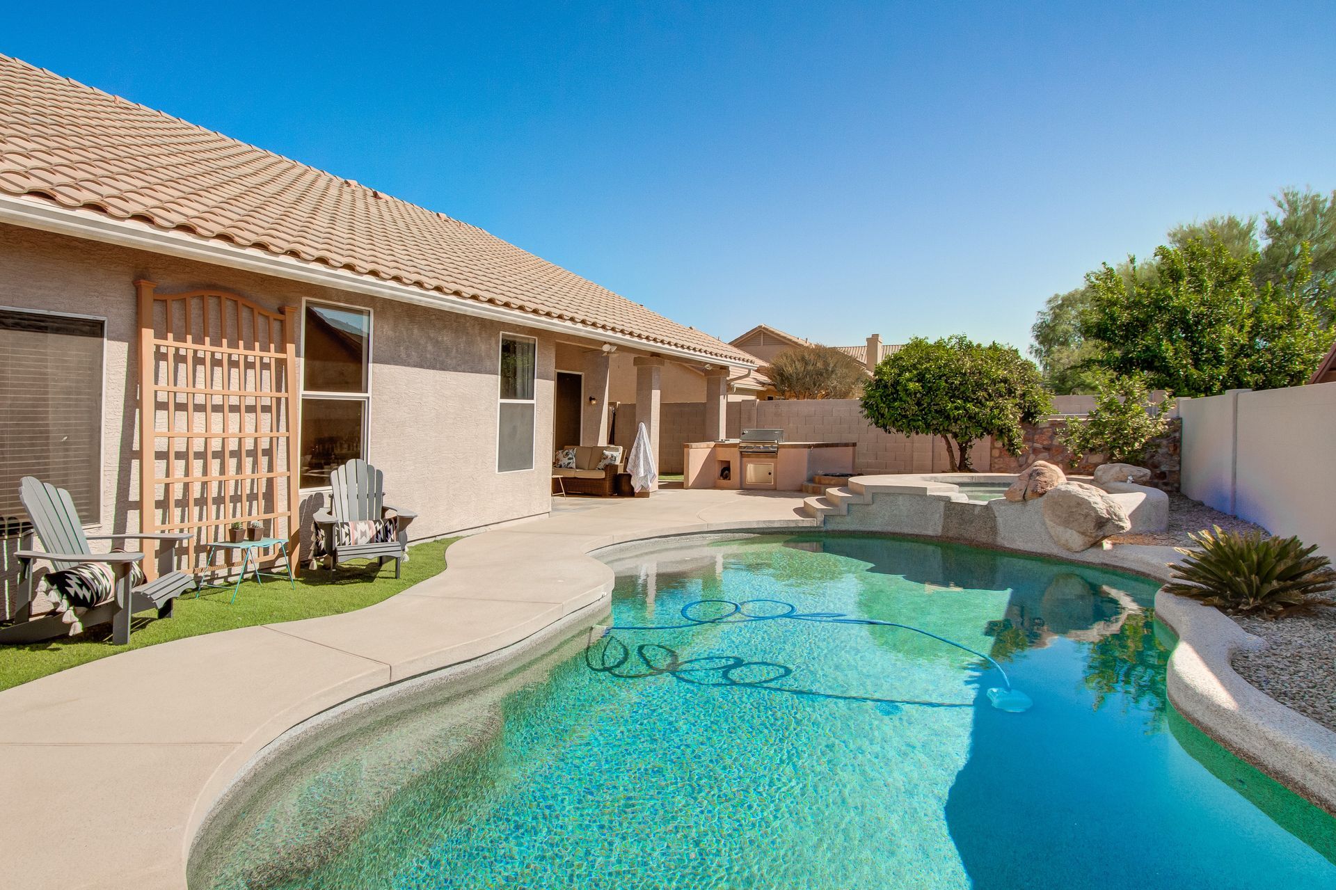 A large swimming pool is in the backyard of a house.