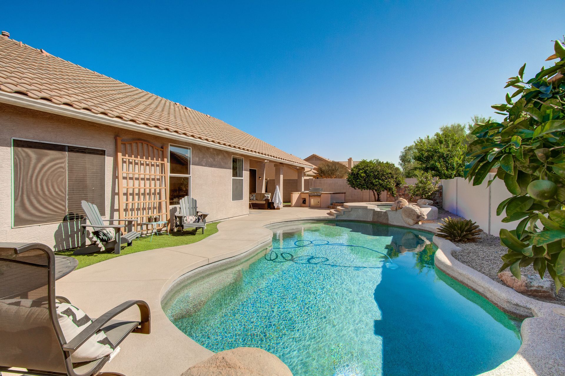 A large swimming pool is in the backyard of a house.
